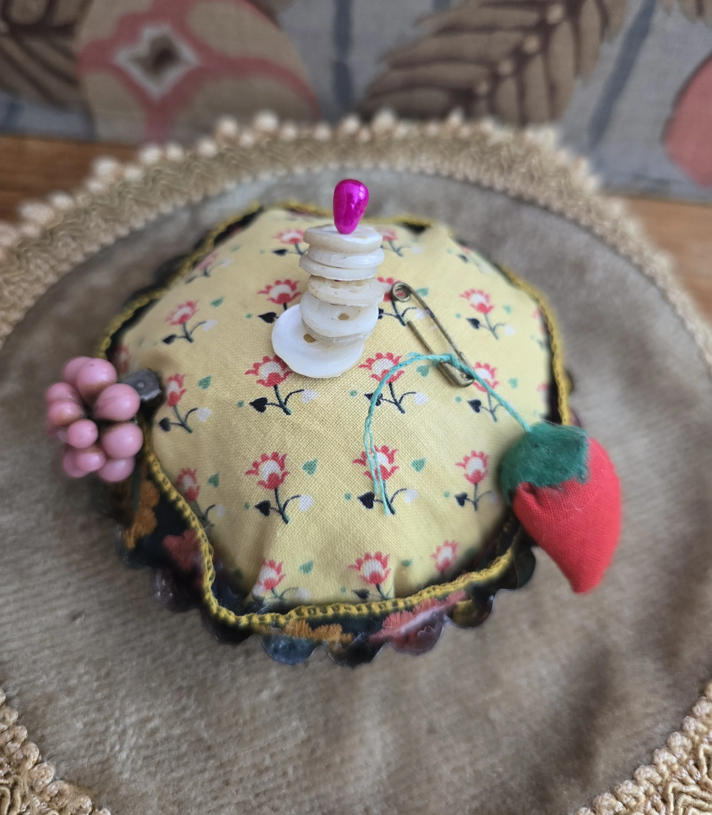 Handmade floral pincushion topped with vintage buttons and a bright pink glass headed pin.