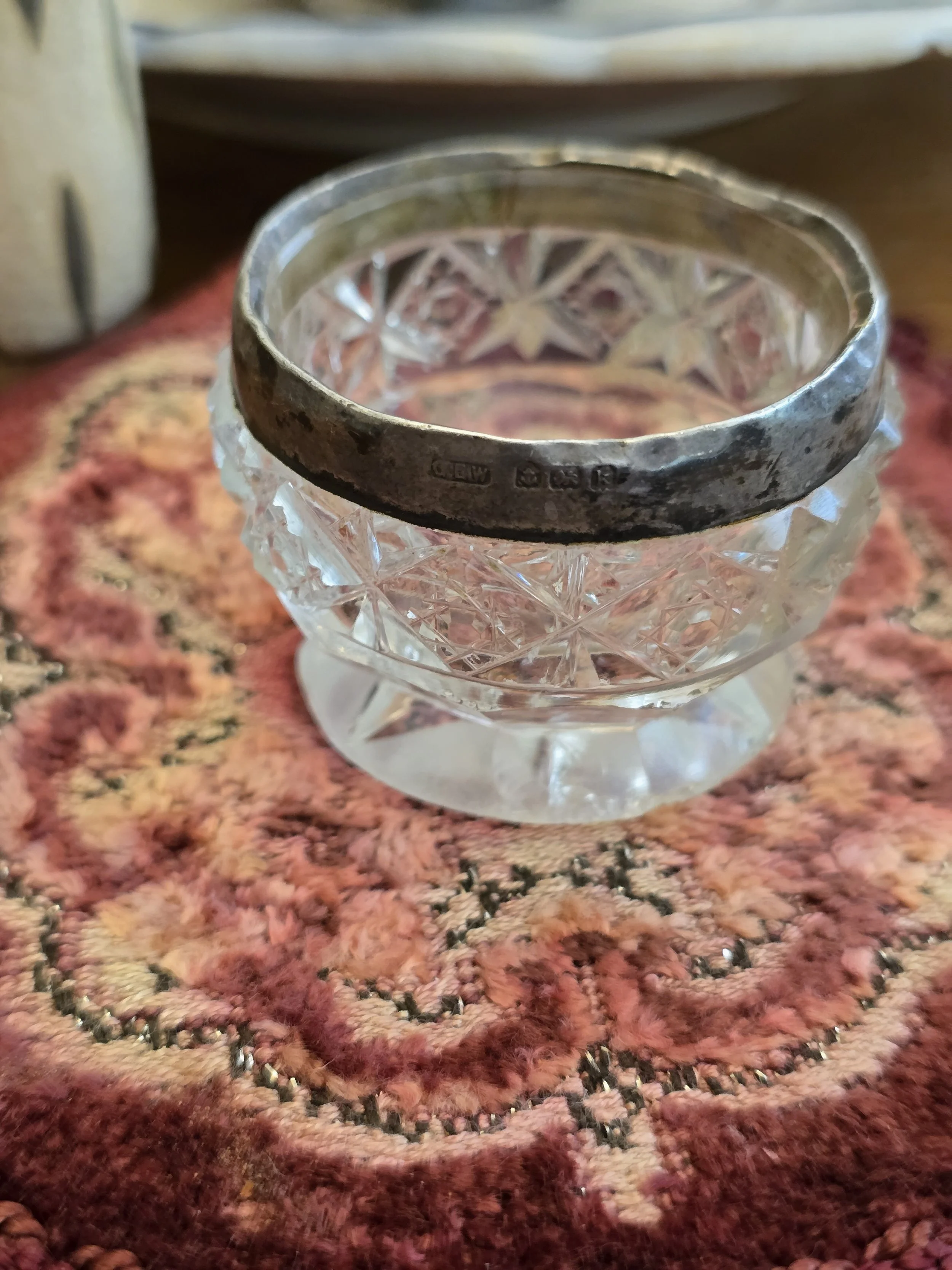 Antique cut glass salt cellar with hallmarked silver rim, dating from the early 20th century.