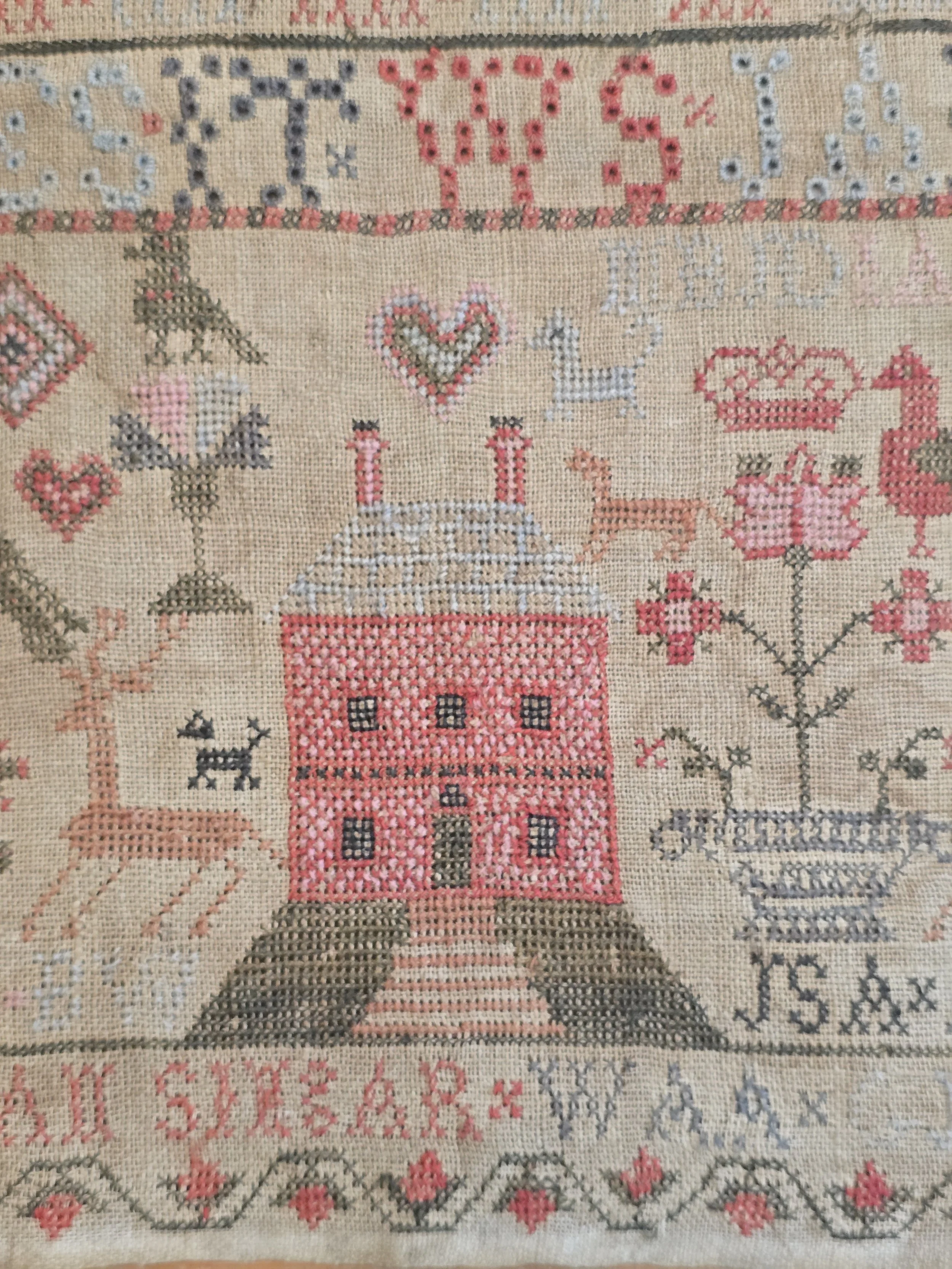 Detail of the embroidered birds, crowns and alphabet rows stitched in faded silk on Georgian linen.