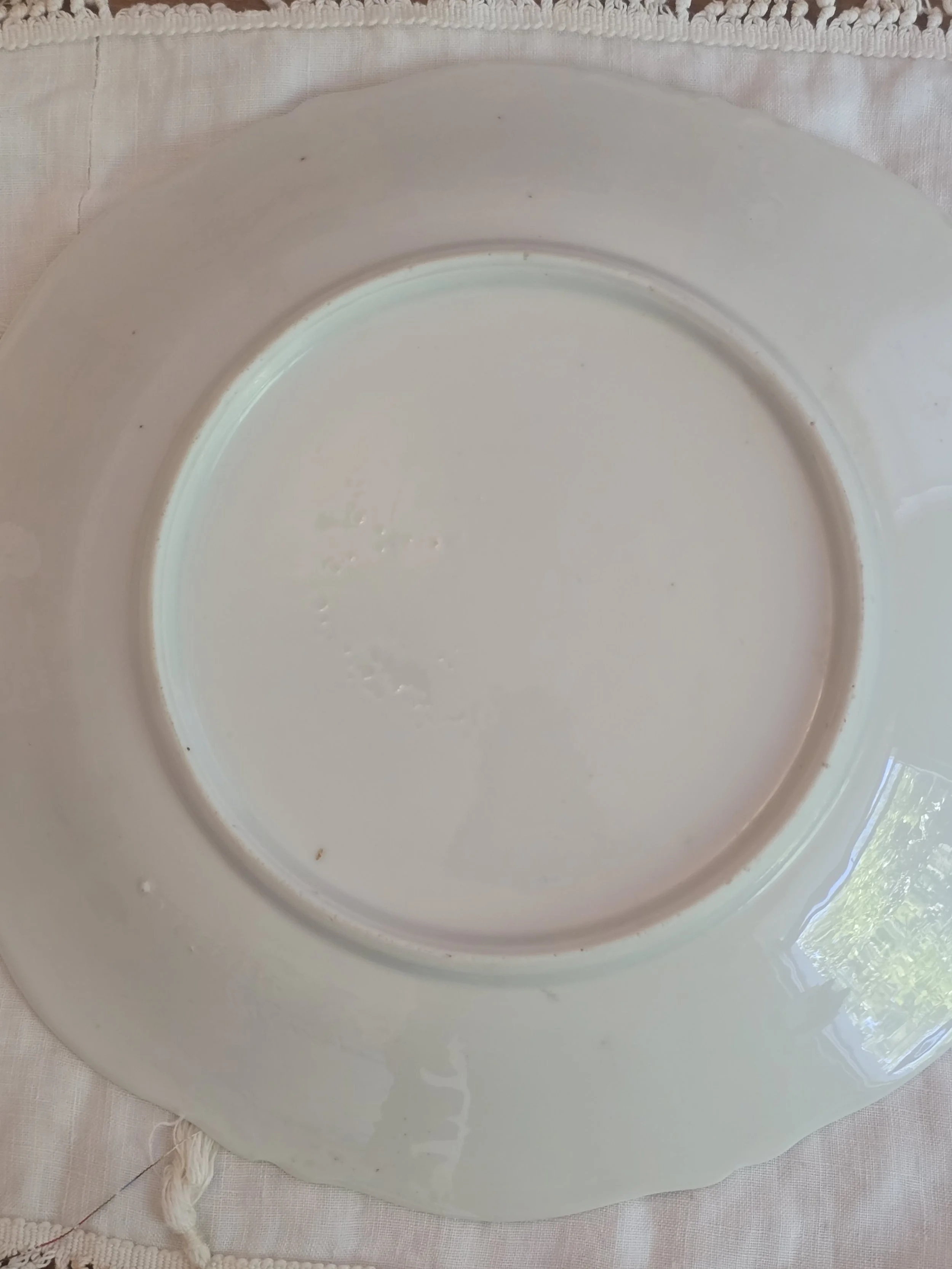 Reverse of vintage German ceramic plate showing faint impressed makers mark