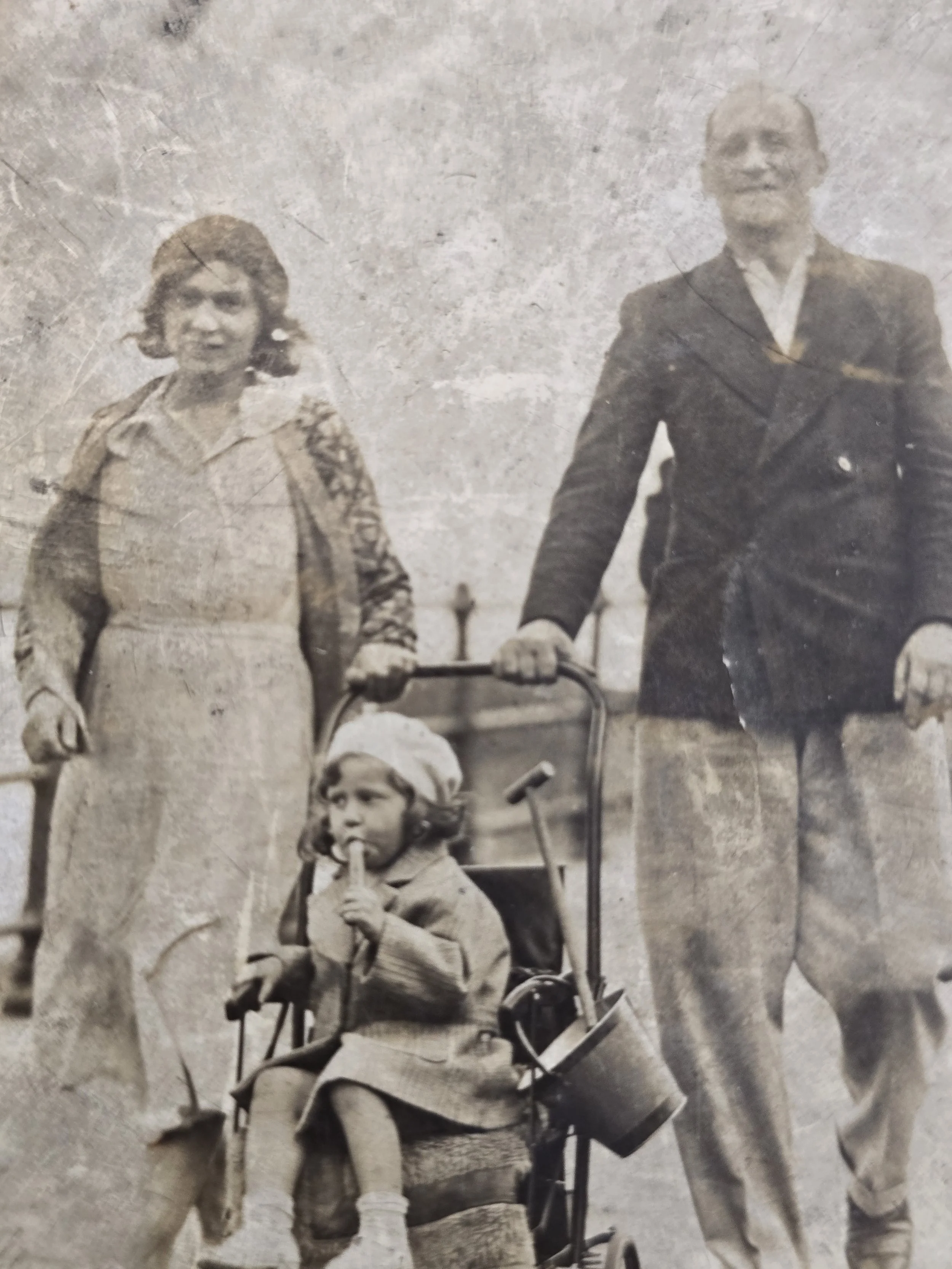 Detail of child seated in a pushchair holding an ice lolly during a seaside holiday.