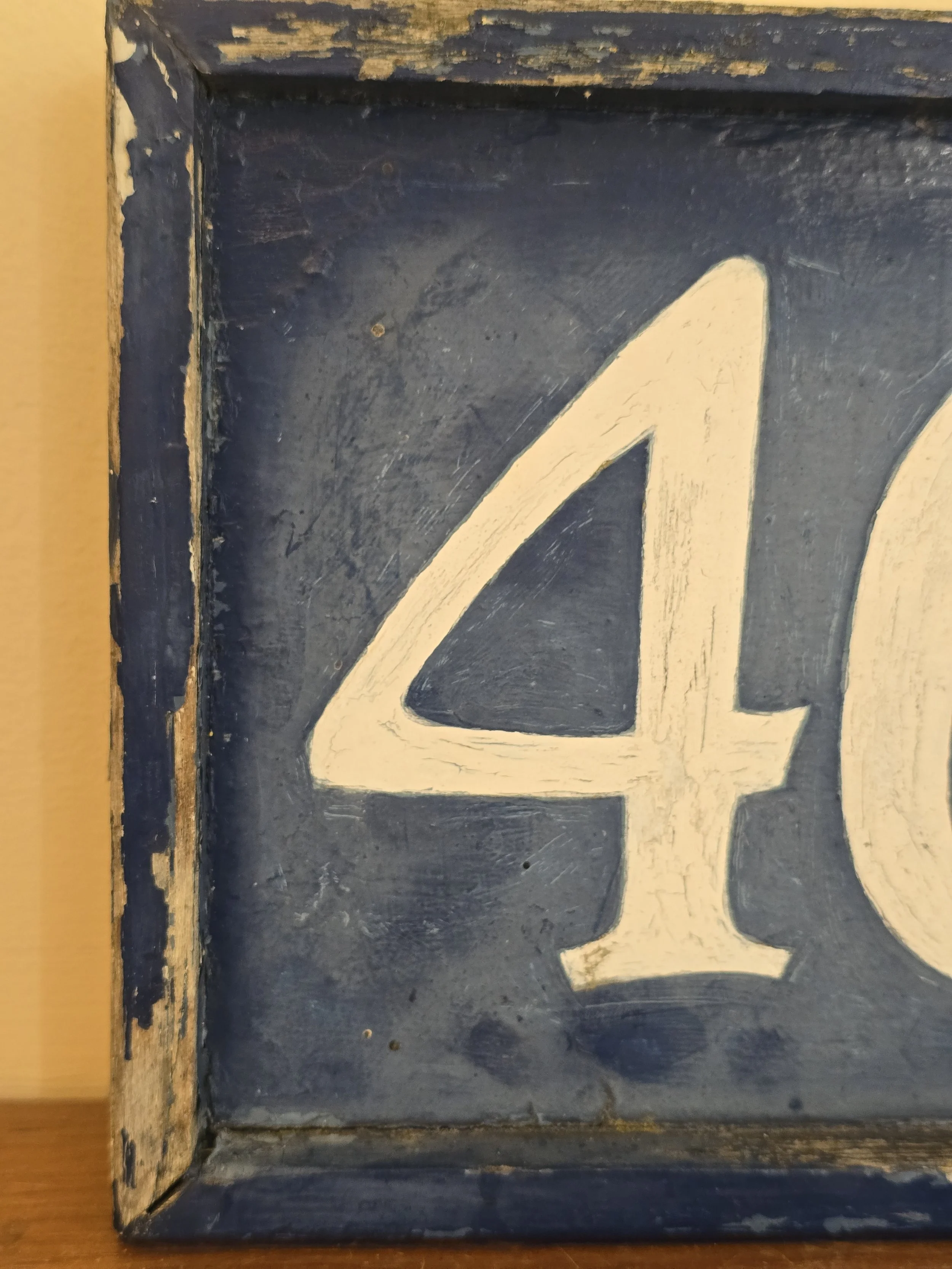 Close-up of distressed paint and weathered patina on antique number sign.
