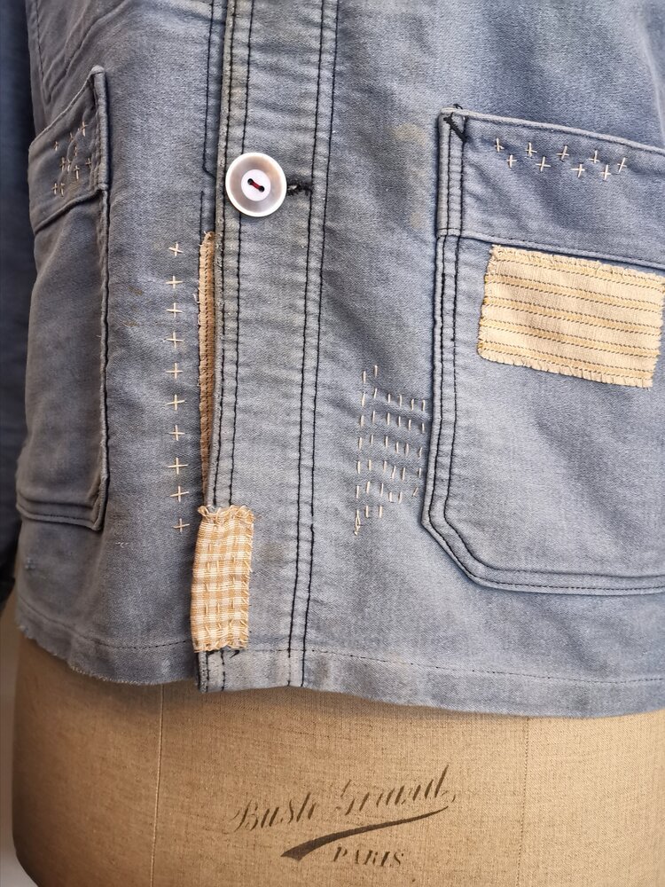 Button Placket – Close-up of central placket with mismatched vintage buttons and repair stitches.