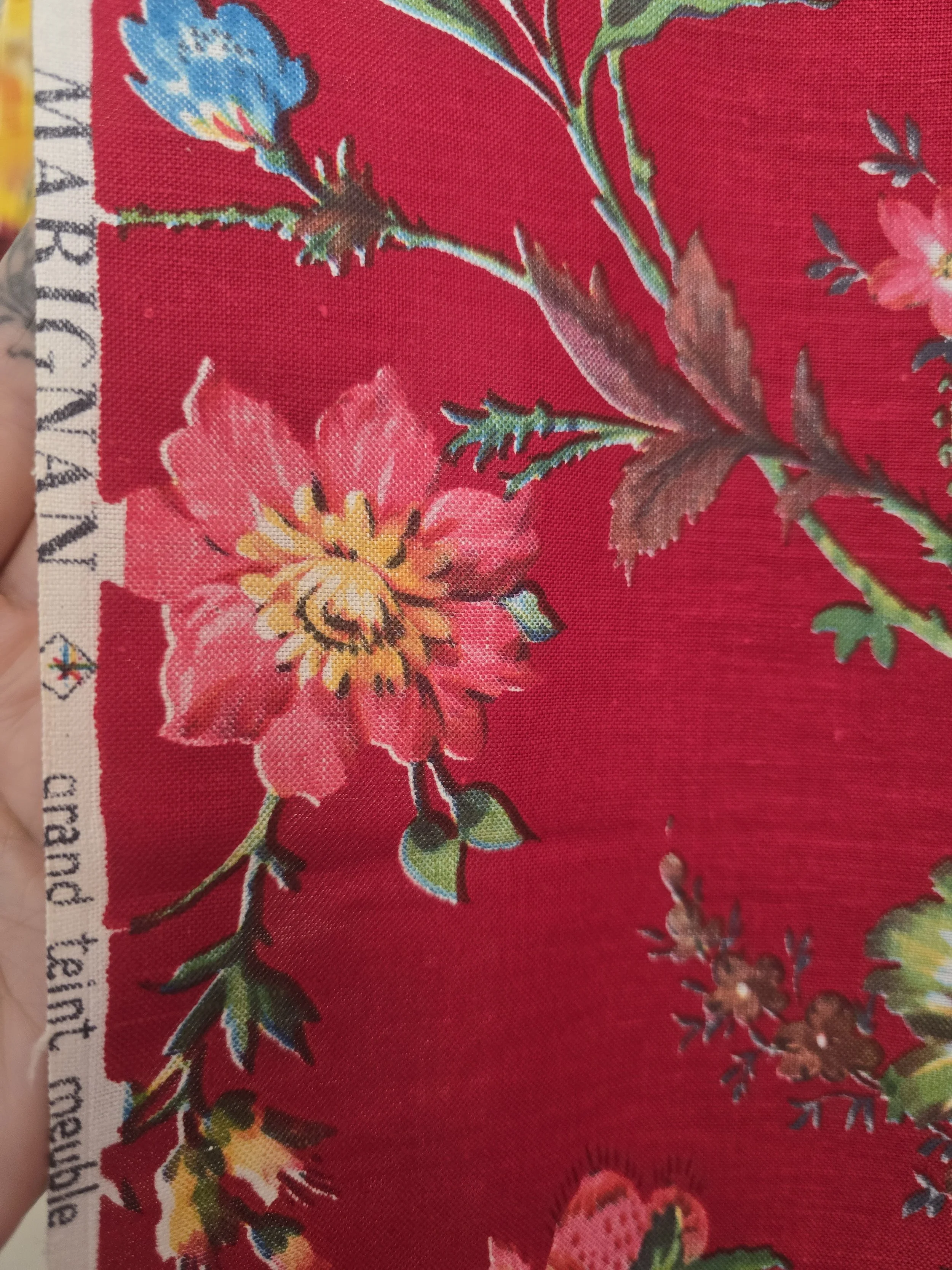Close-up showing the woven texture and colourful floral print of unused vintage furnishing fabric.