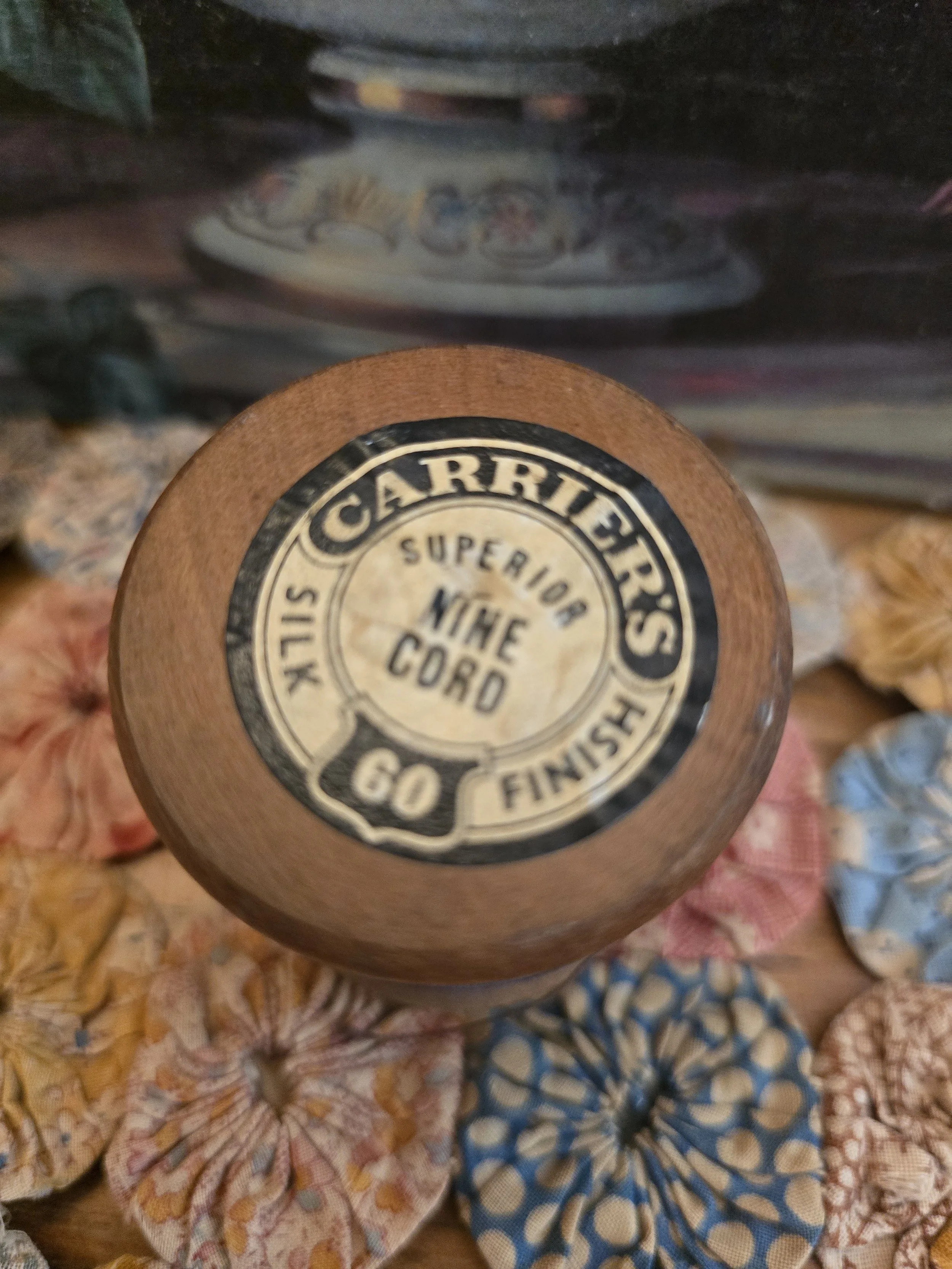 Antique wooden sewing thread spool wound with slate blue thread and retaining original Carriers branding label.