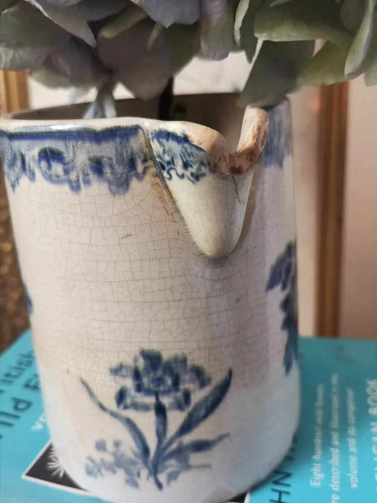 Close-up of blue and white antique ceramic jug spout repair