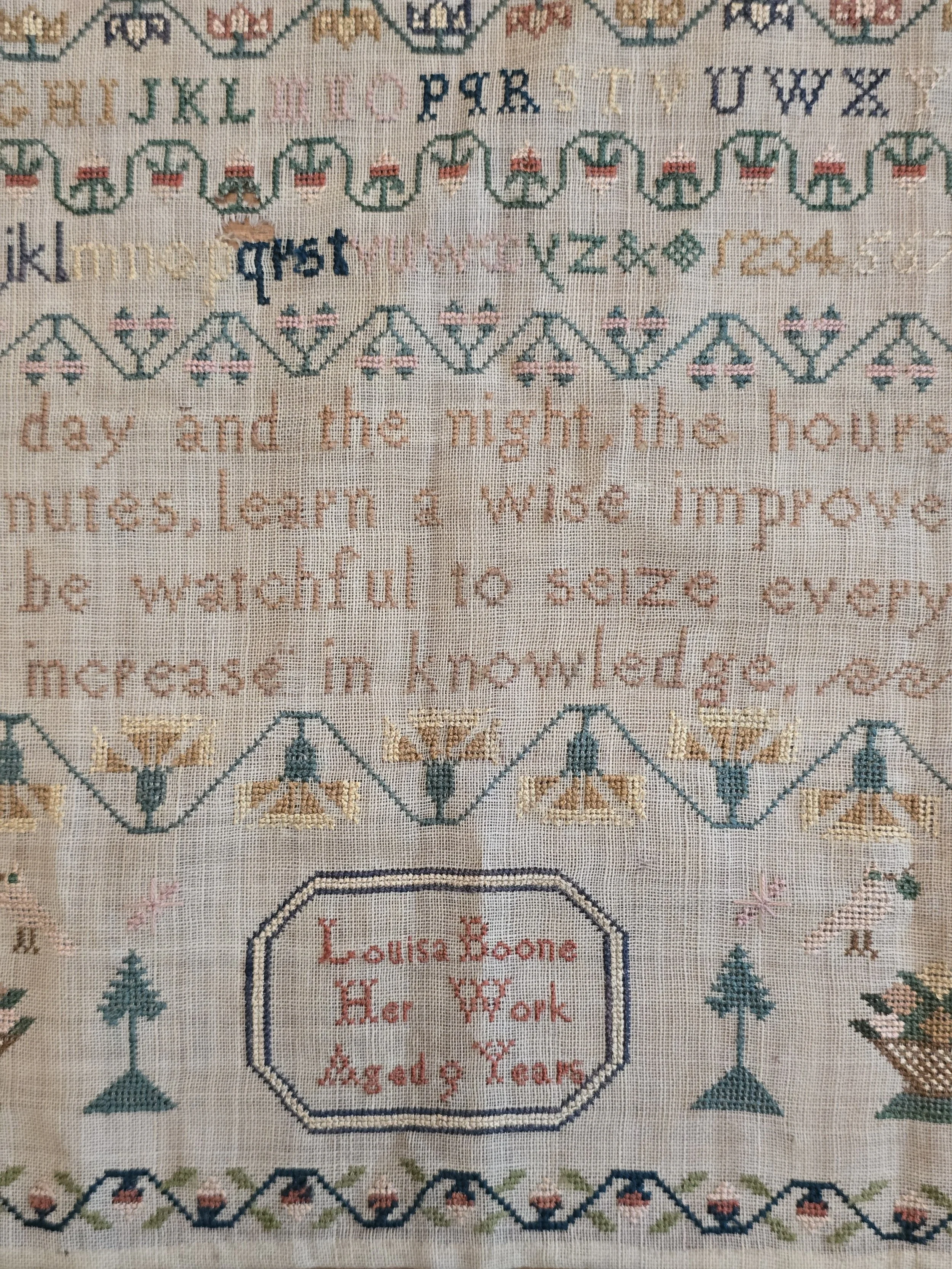 Early 19th century schoolgirl sampler embroidered by Louisa Boone aged 9 years with alphabets, birds, baskets and decorative borders on linen.