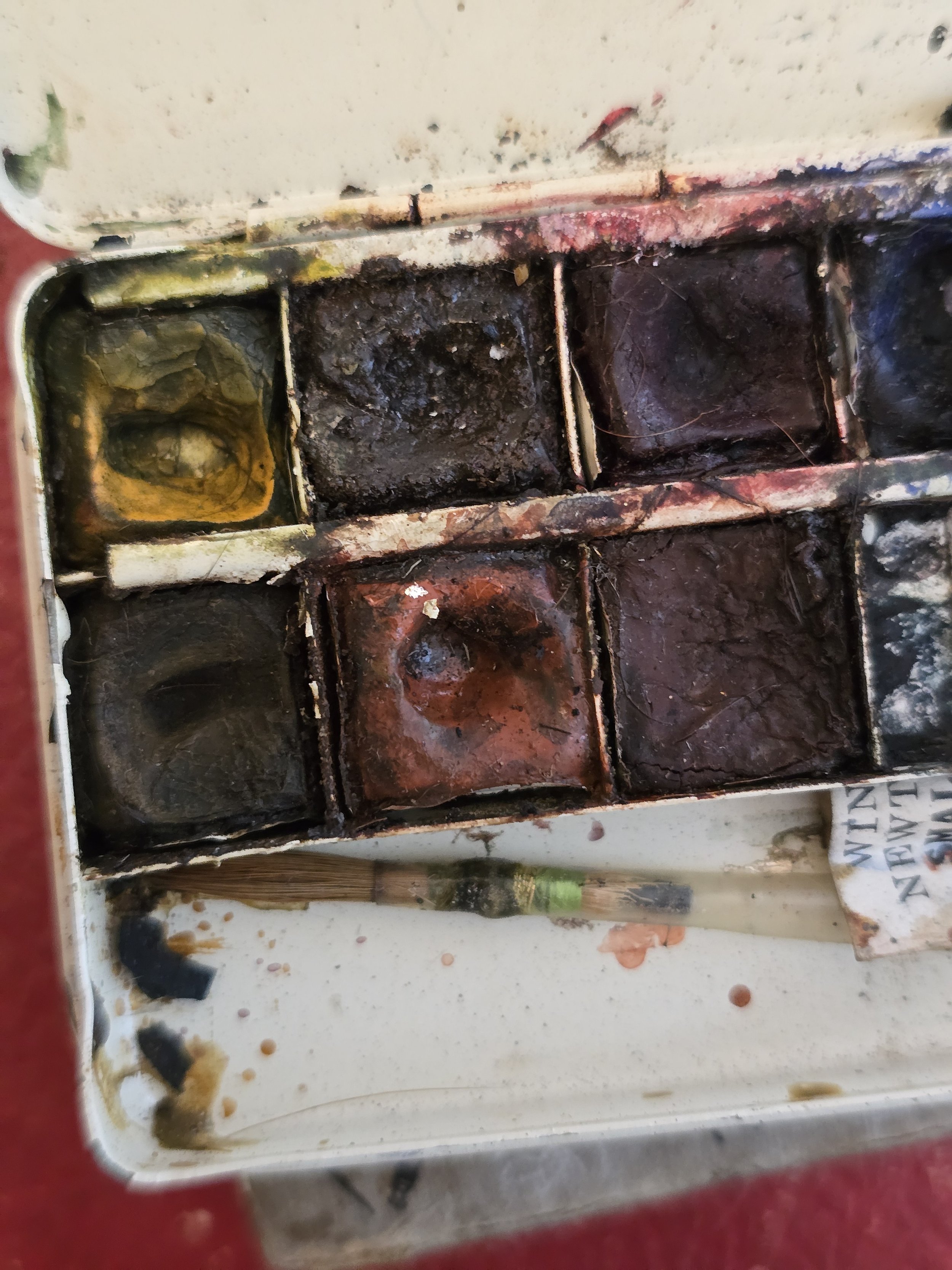 Interior of vintage watercolour box showing original paint pans and brush.