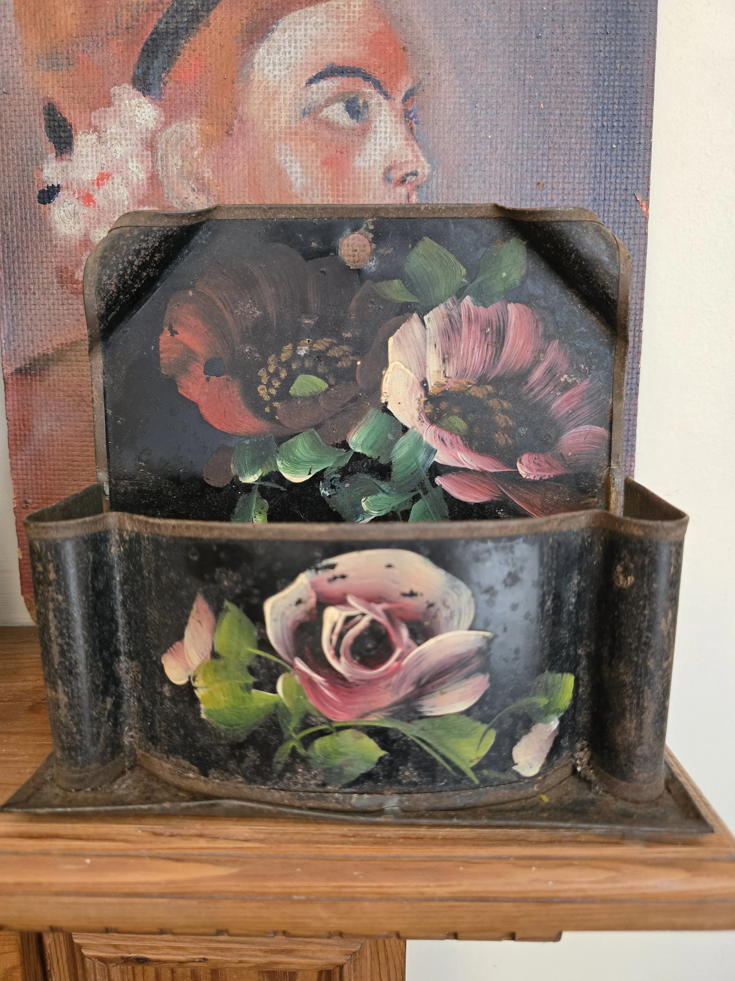 Vintage hand painted floral tole wall pocket with pink roses and aged black metal finish.