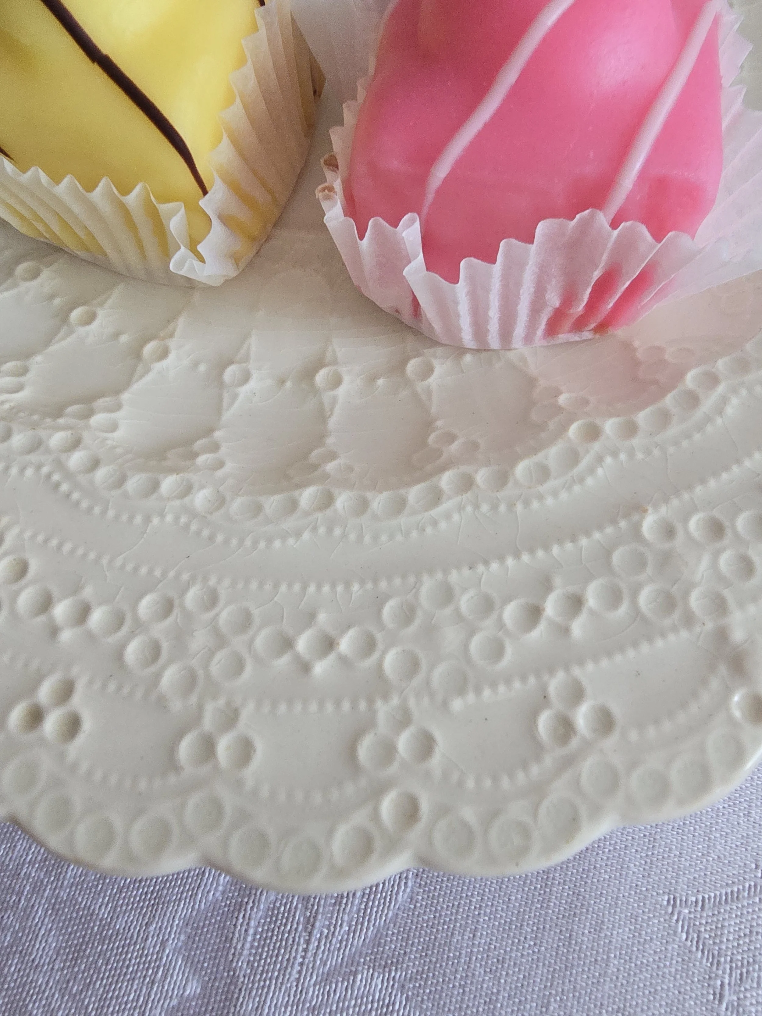antique white ceramic plate with embossed lace pattern and scalloped edge detail