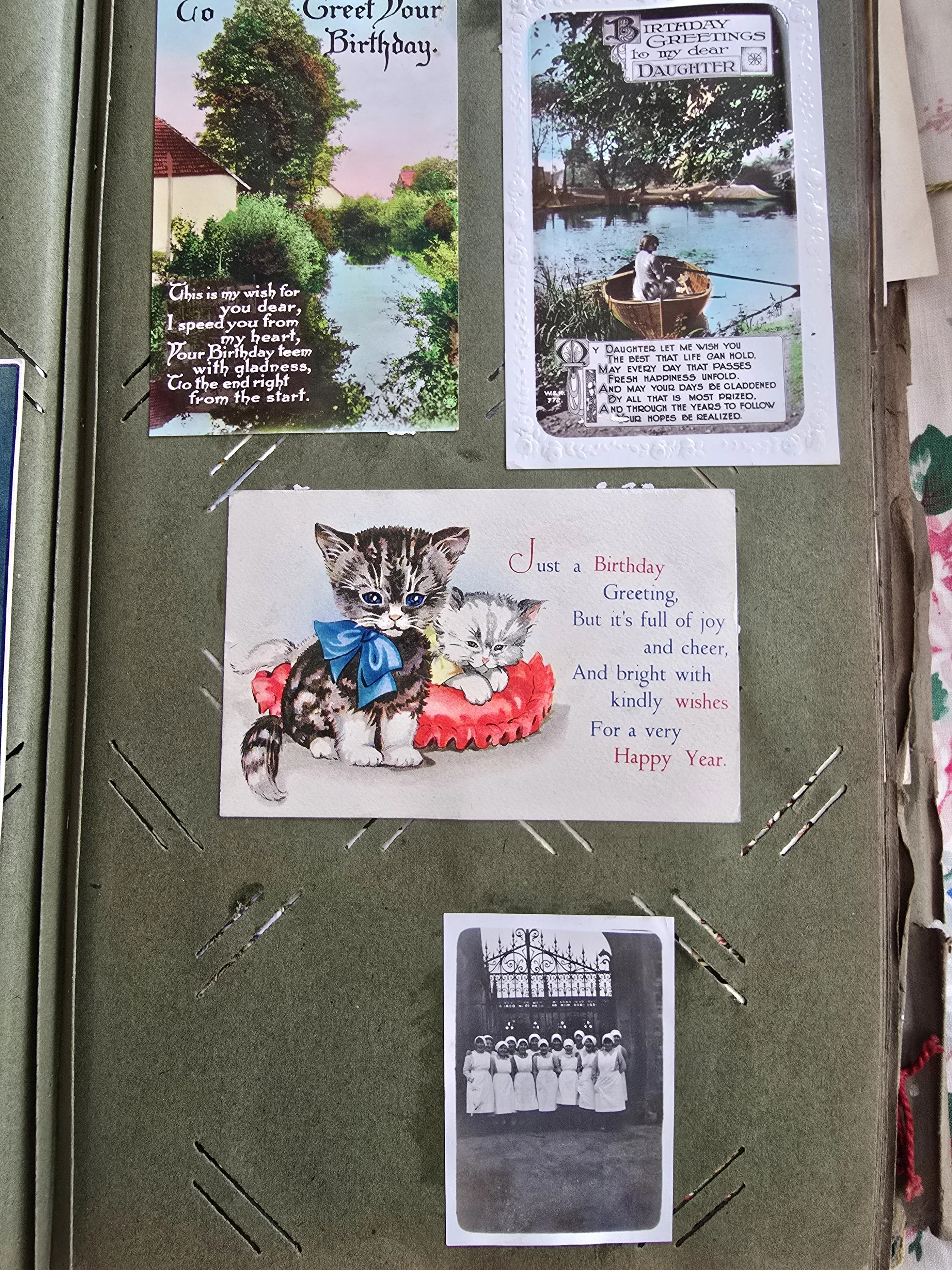 Vintage scrapbook page with birthday postcards including kittens, countryside scenes, and a black and white photo of nurses.