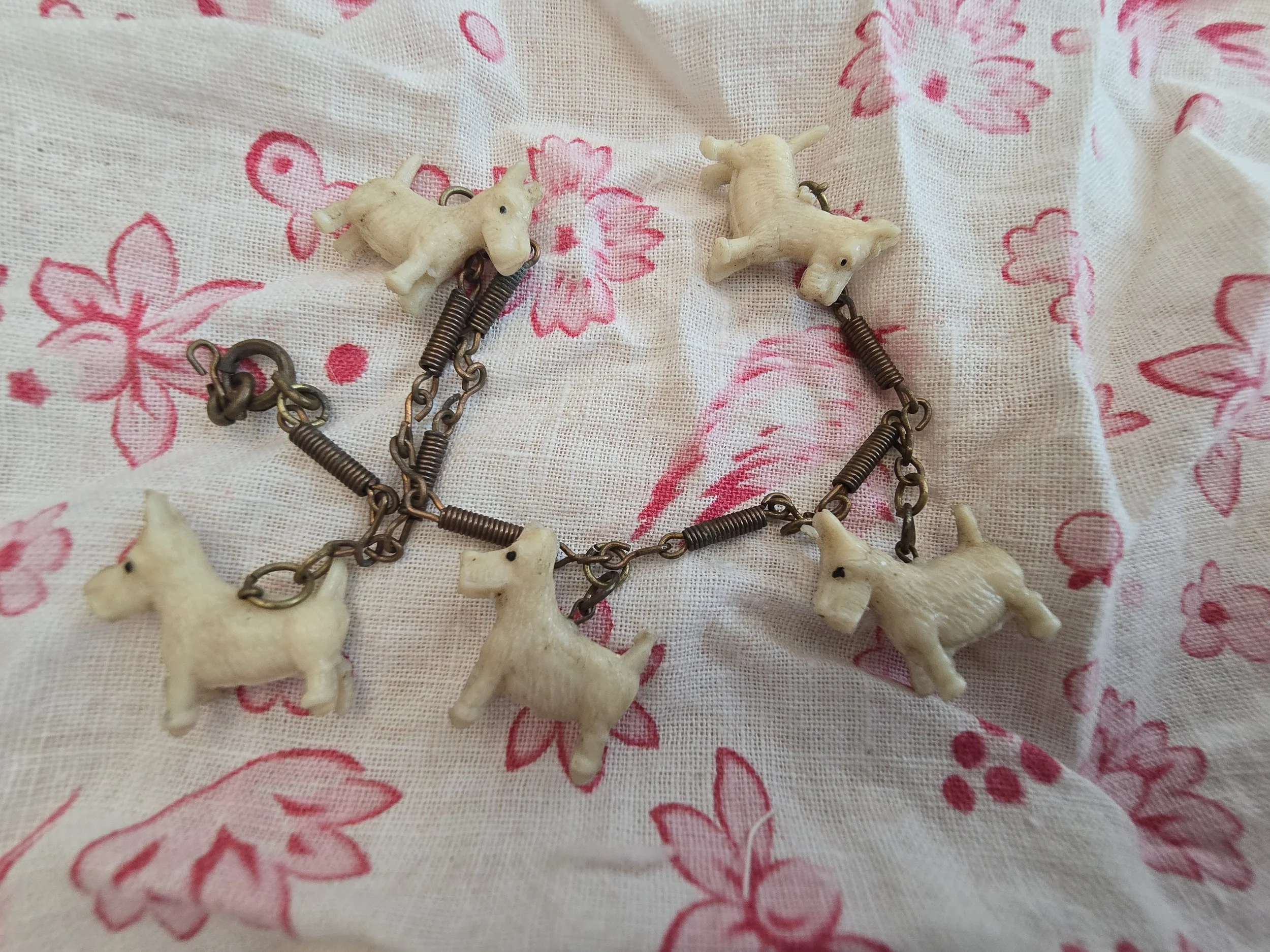 Vintage bracelet featuring five cream-coloured Scottie dog charms linked by aged metal chain.
