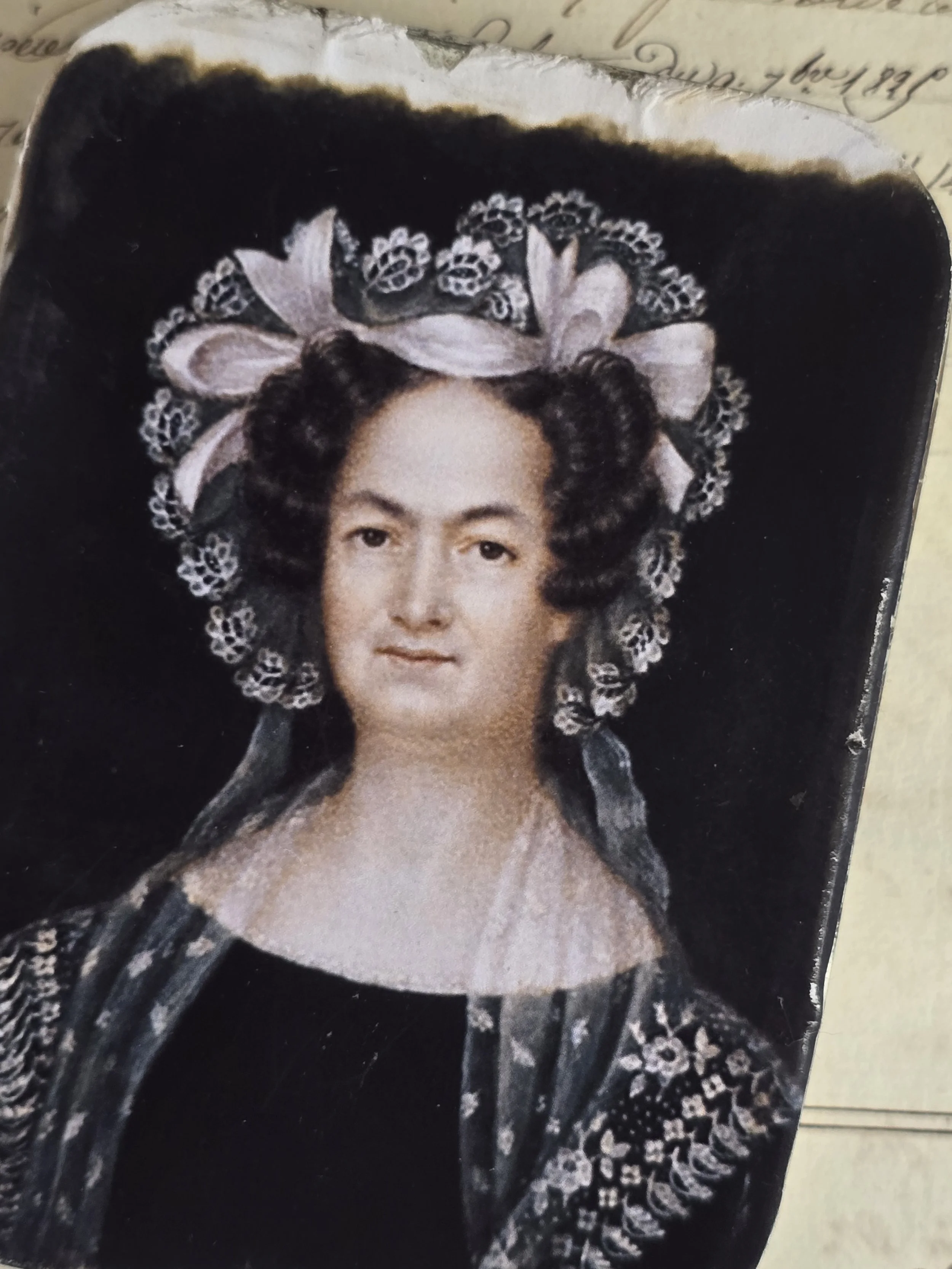 Close-up of historic female portrait applied to a small timeworn vintage tin, showing gently distressed edges.