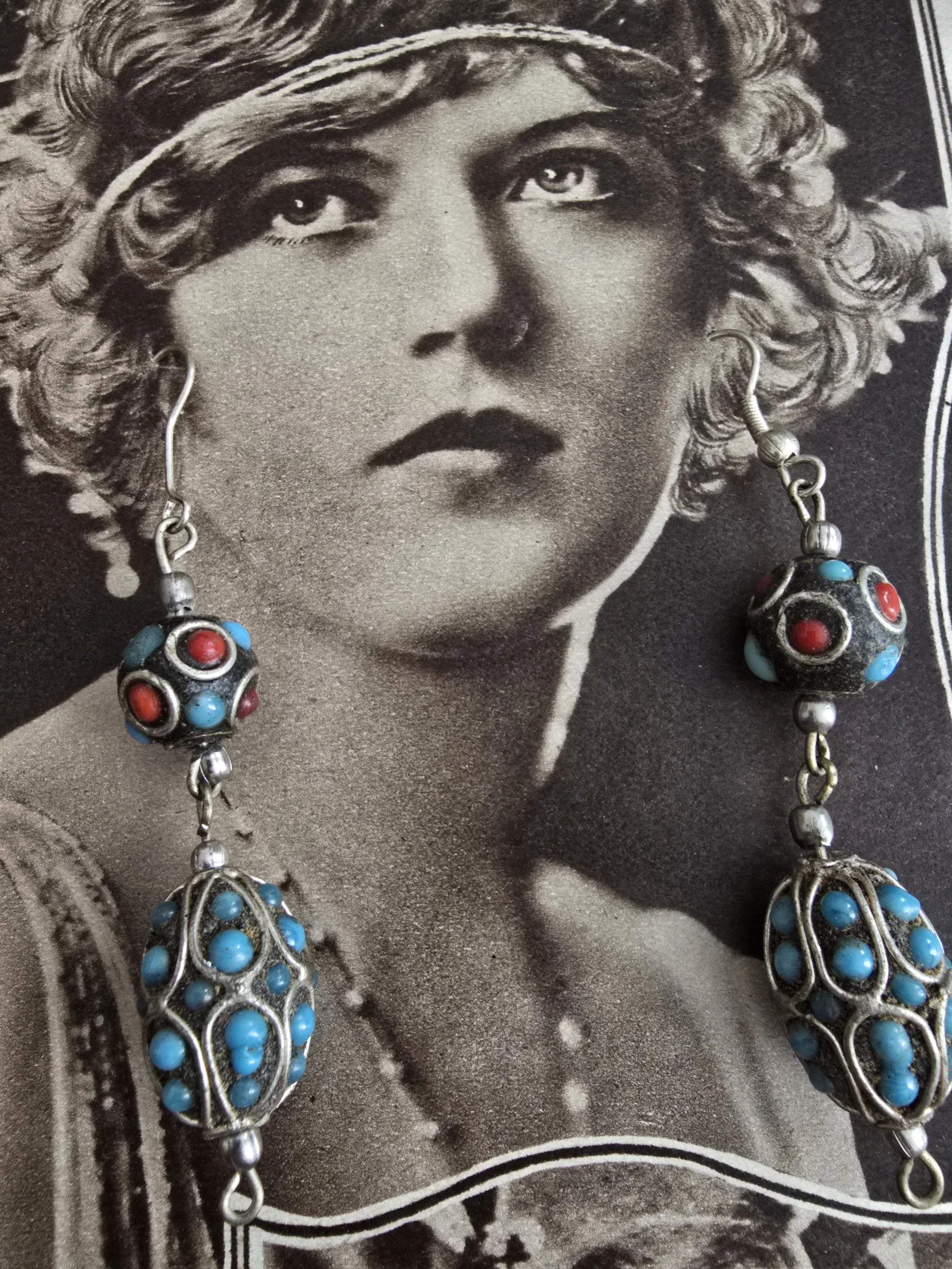 Close-up of Tibetan-style earrings with detailed silver-toned filigree and bright blue beads