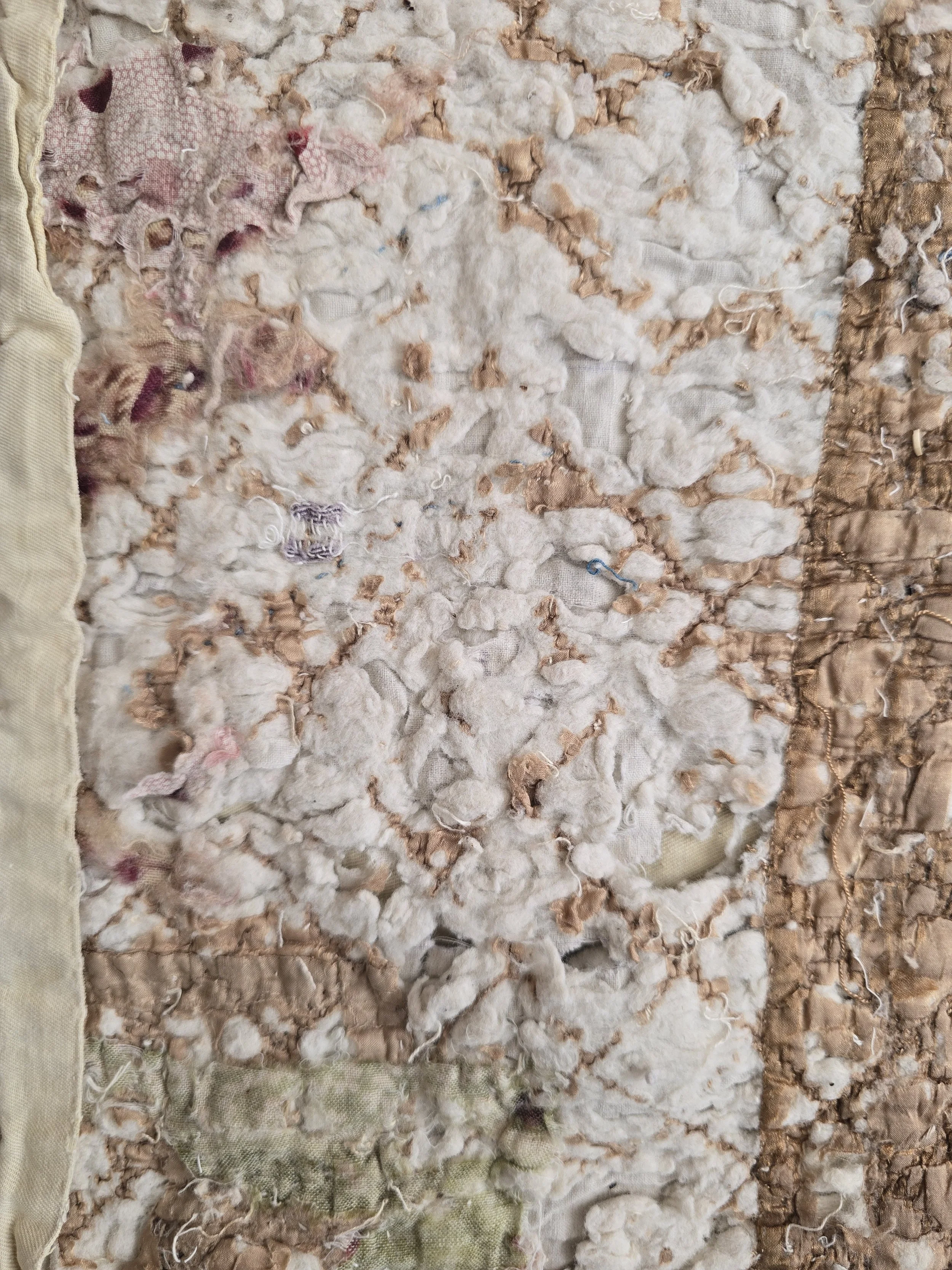 Antique French quilt fragment with faded purple printed cotton and exposed layers.