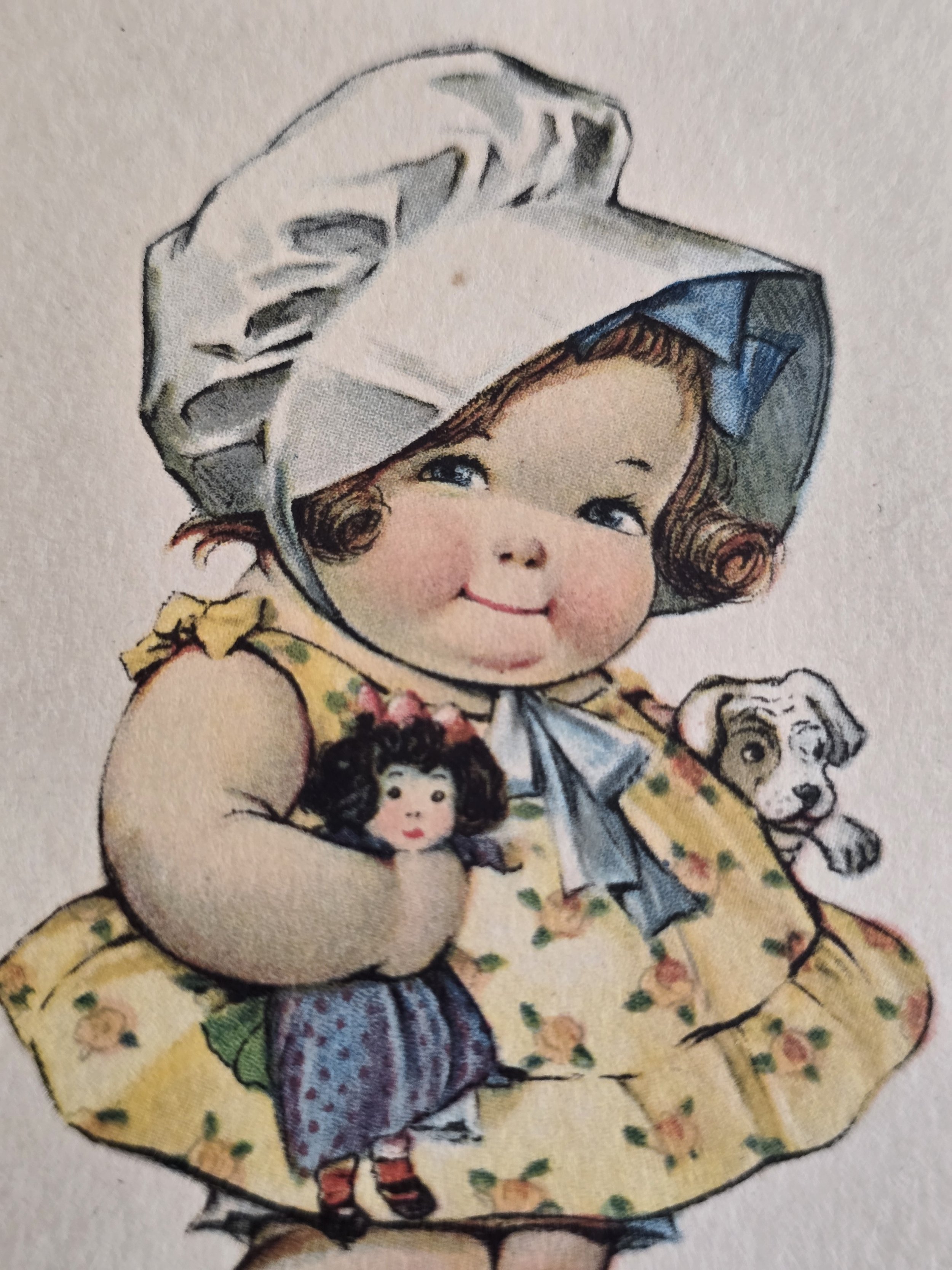 Close-up of smiling bonneted child holding doll on vintage postcard