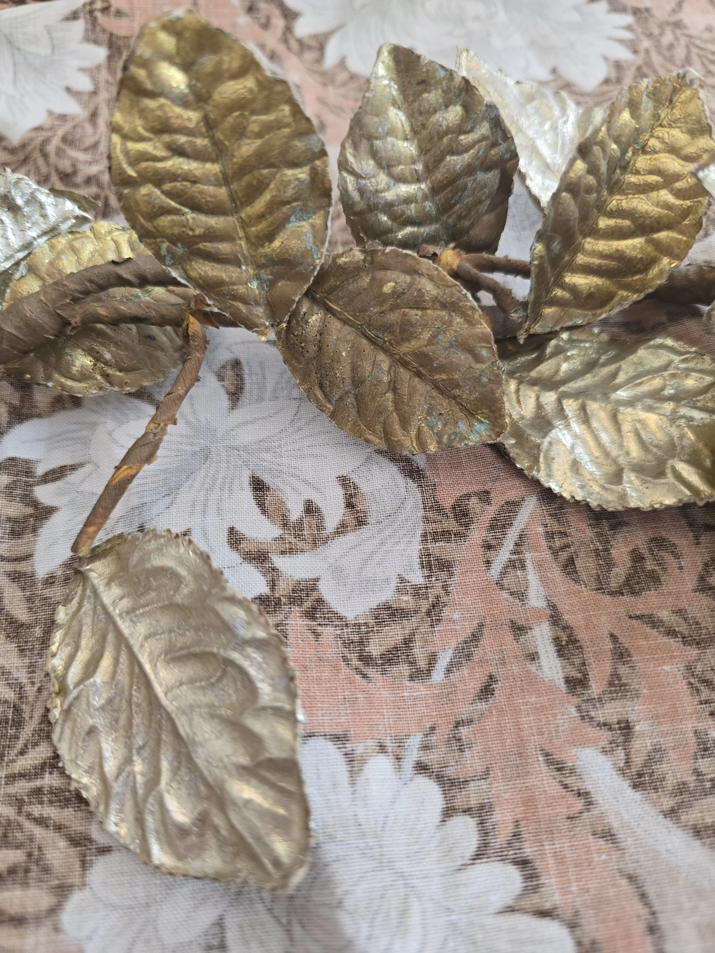 Close view of sculpted gilded rose bloom with layered metallic petals.