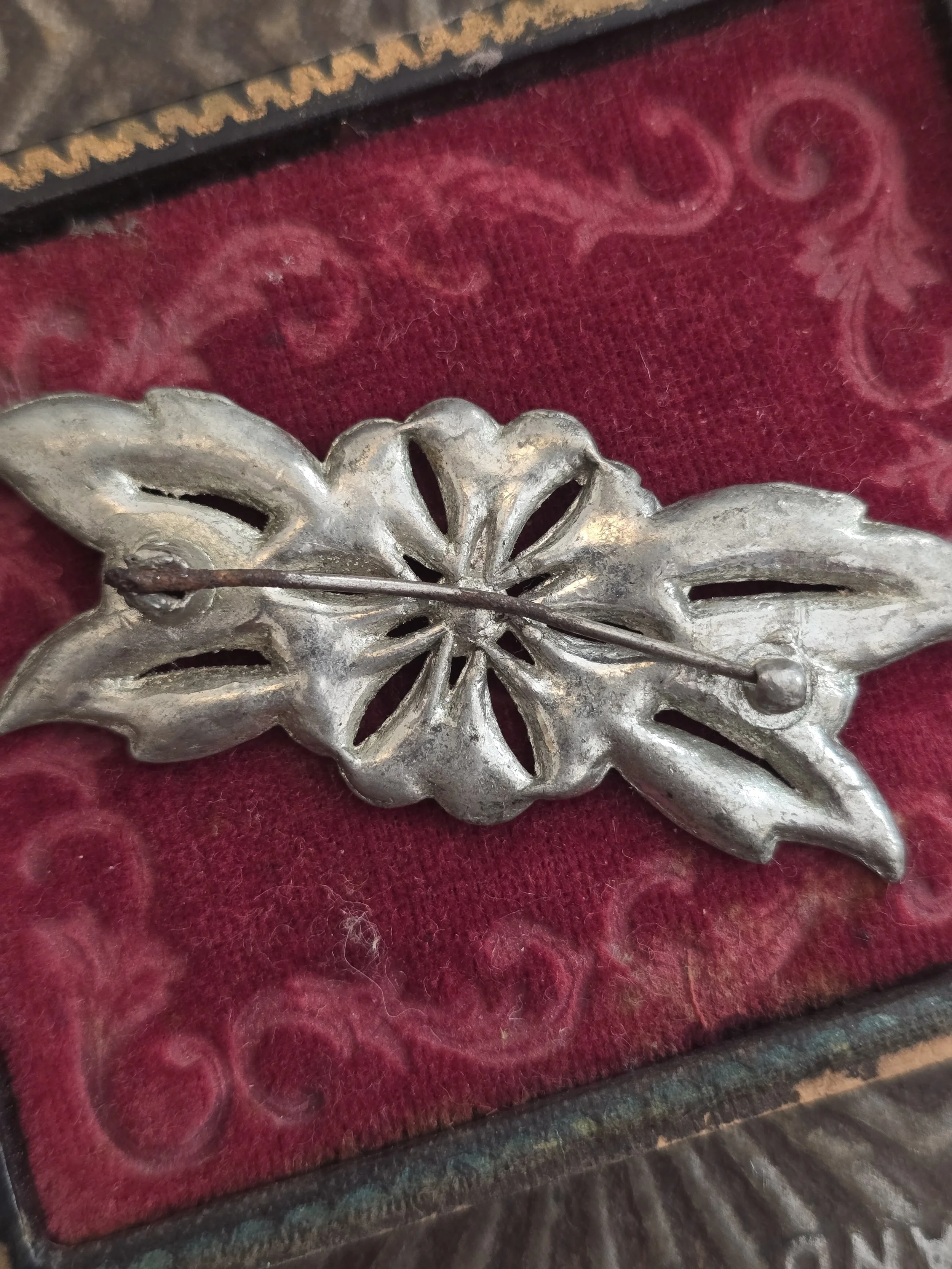 Reverse of vintage floral brooch showing original pin fastening and openwork construction.