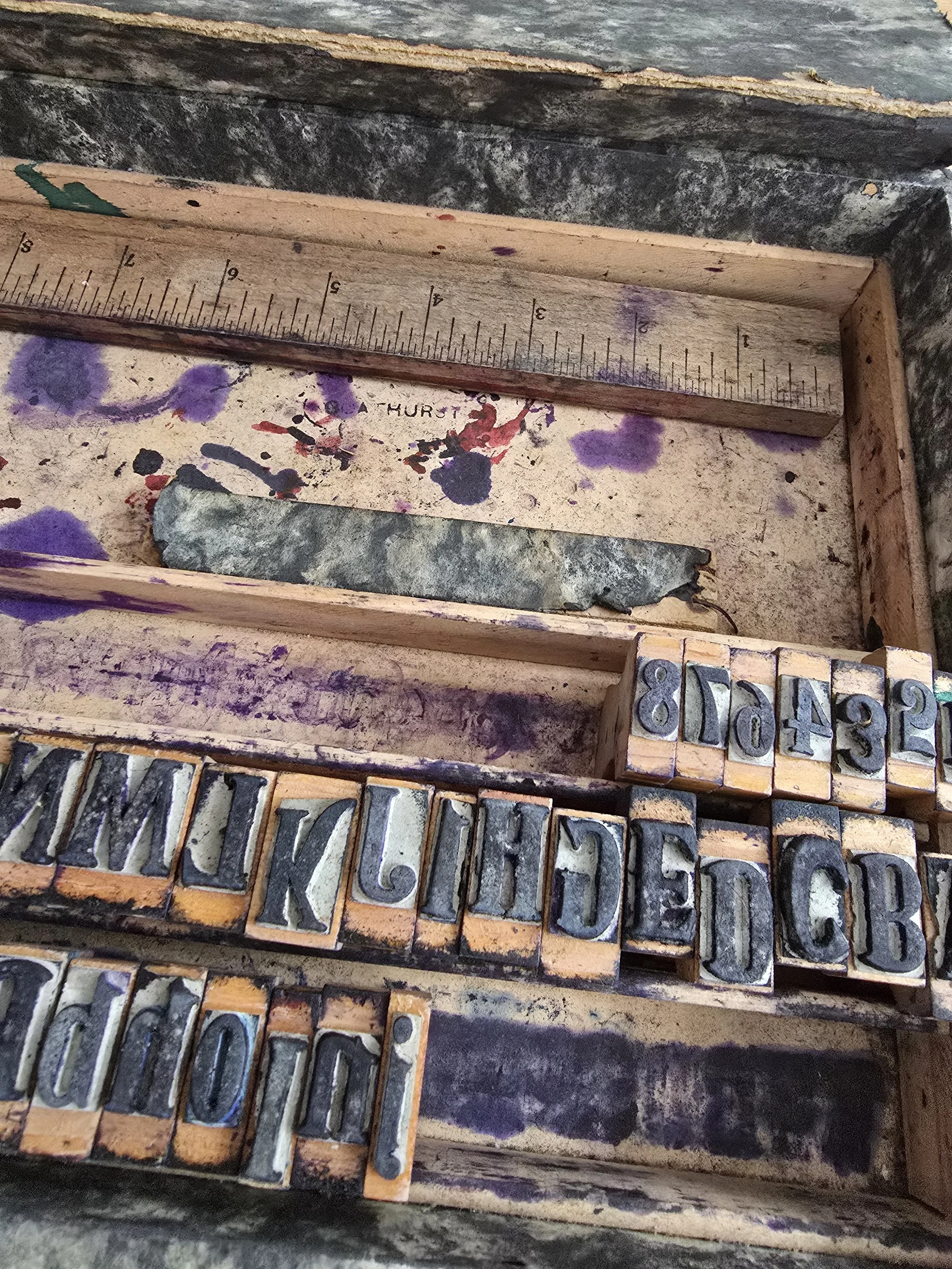 Detail of antique stamp box showing ruler and purple ink stains.