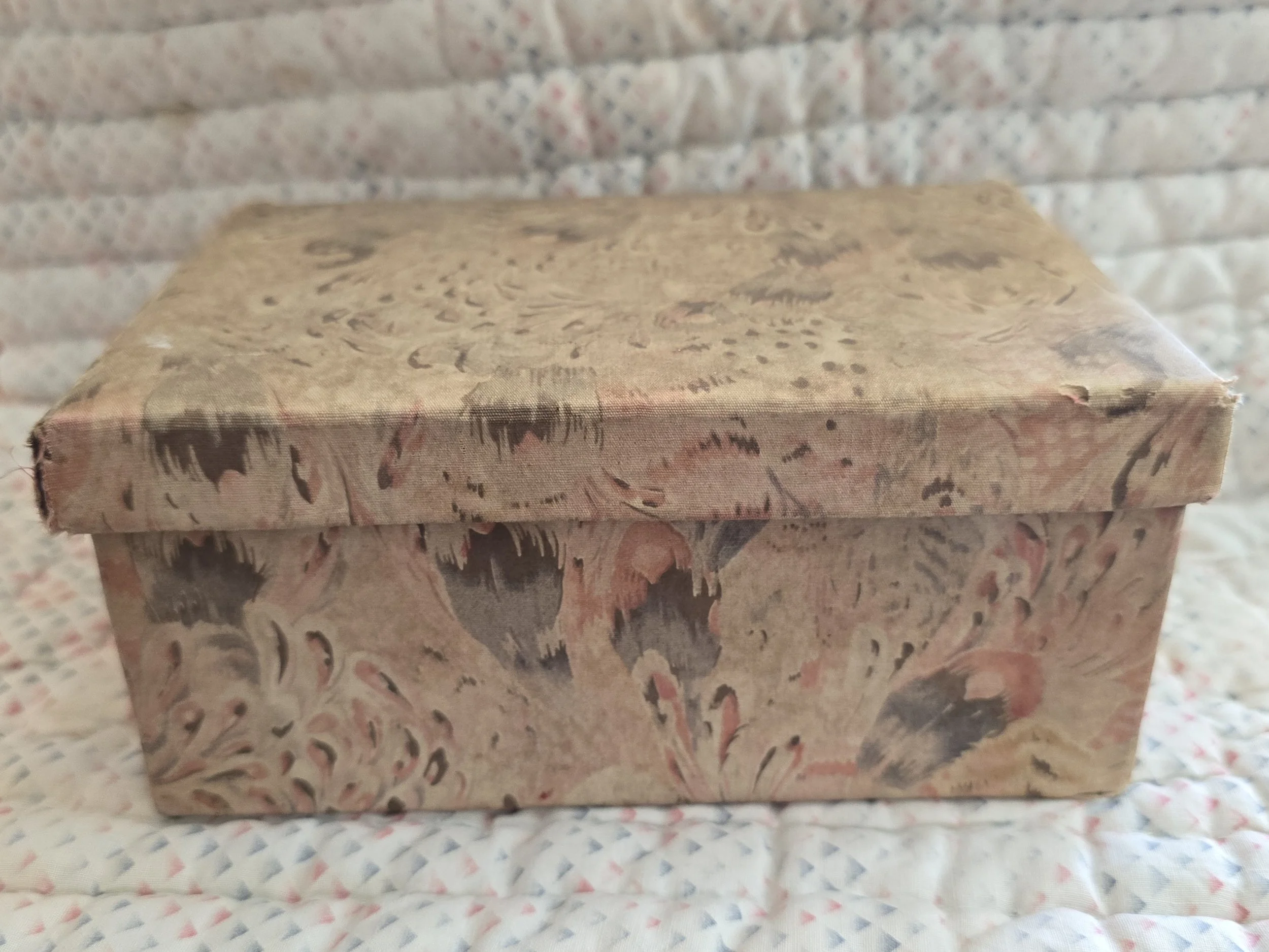 Vintage fabric-covered keepsake box with faded floral abstract pattern in blush and taupe tones.