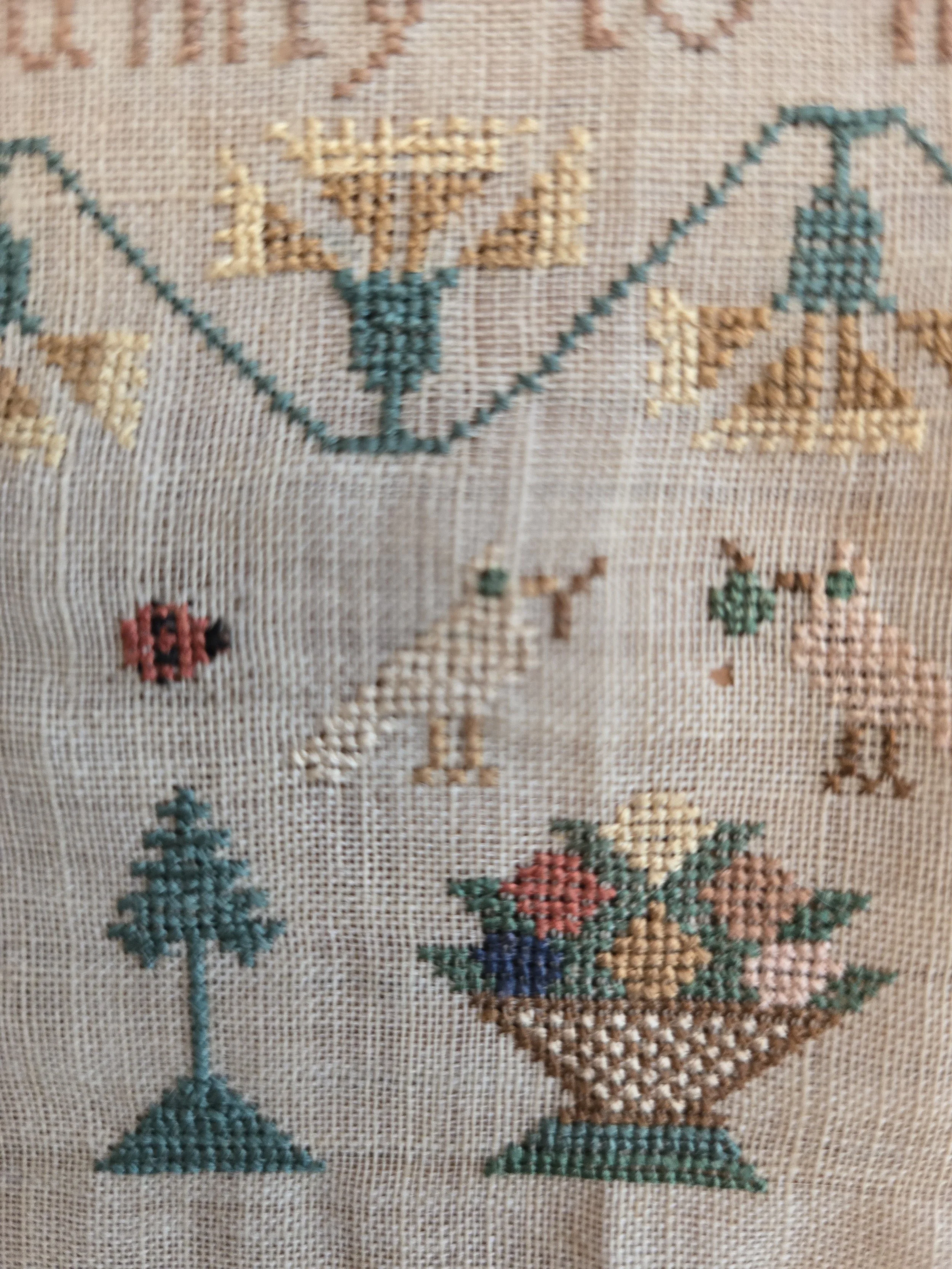 Unframed early nineteenth century schoolgirl sampler with folk art motifs and hand stitched verse.