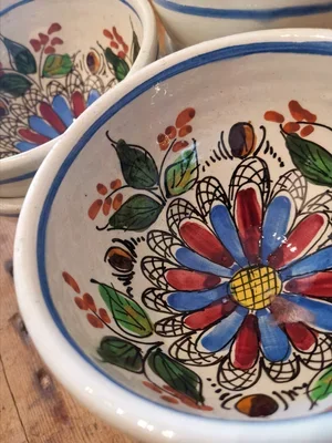 Detail view of vintage French rustic pottery bowl, hand painted floral decoration in bold colours.