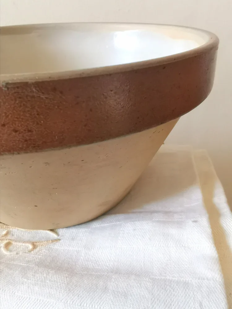 Side view of vintage French stoneware bowl with unglazed exterior and glazed interior