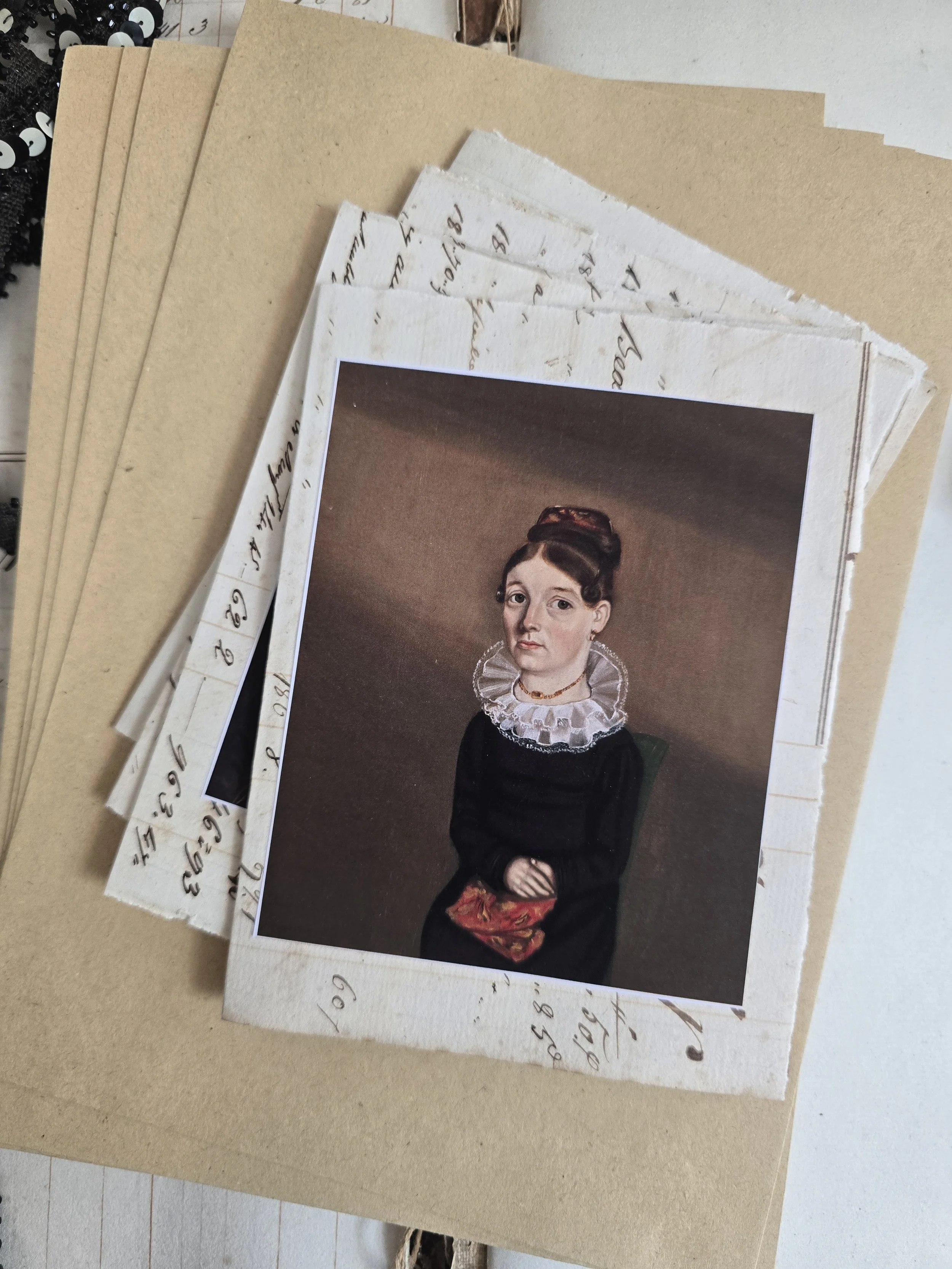Handmade portrait card showing a seated woman in a black dress and white ruff, mounted onto original 1829 French ledger paper.