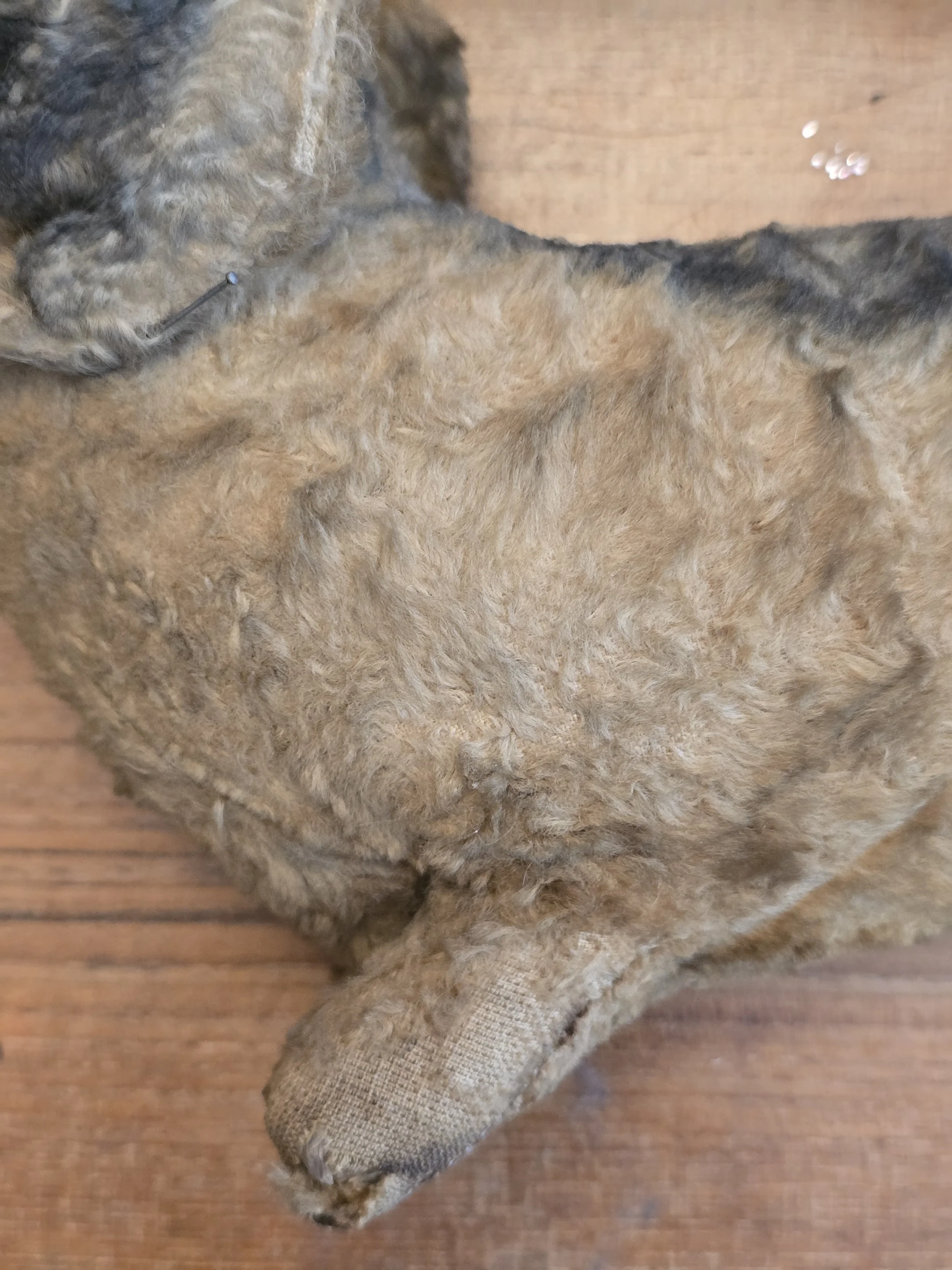 Well loved antique toy dog with age worn character and repairs.