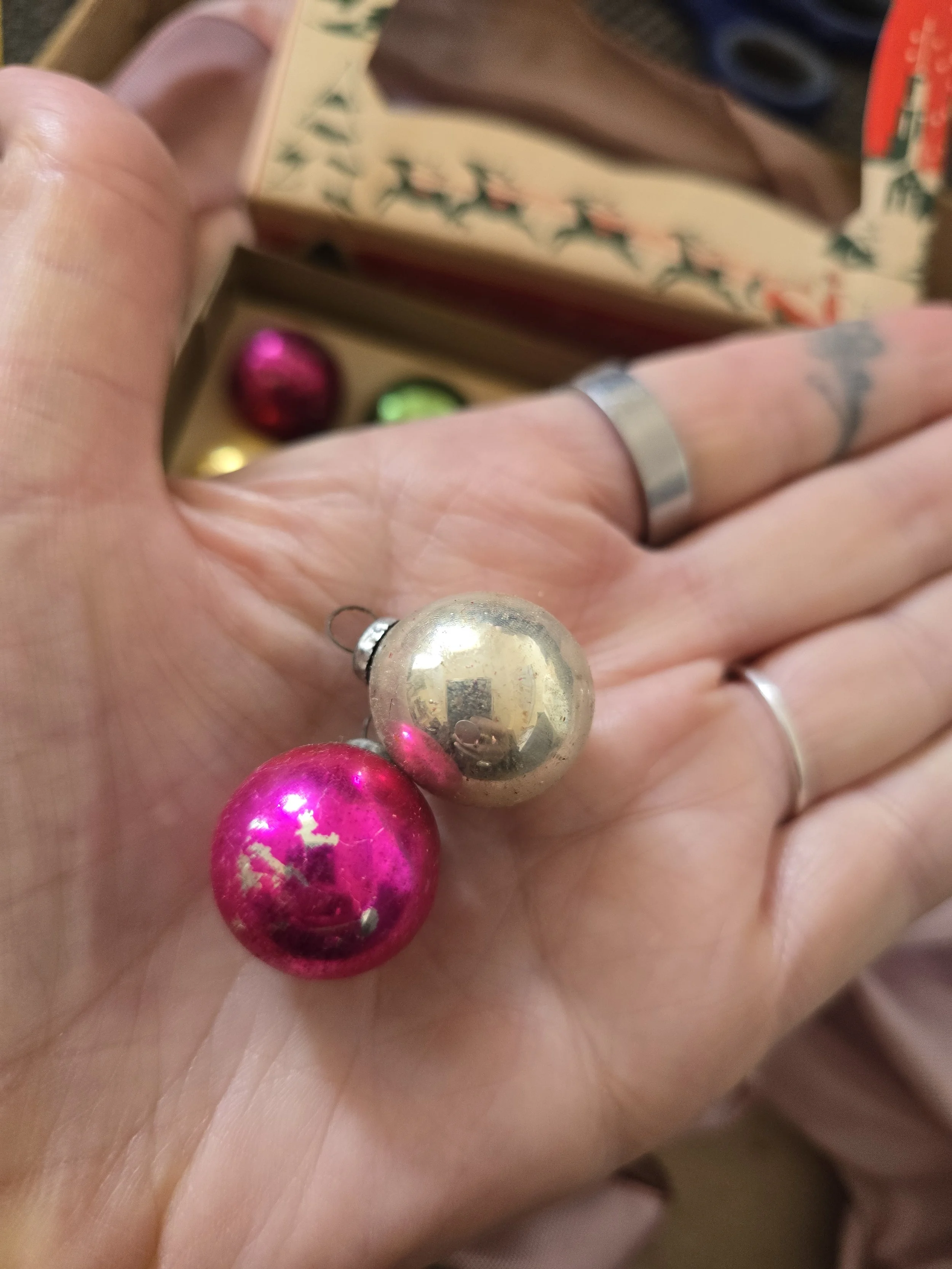 Two miniature vintage glass Christmas baubles measuring approximately 20 mm, shown in hand for scale.