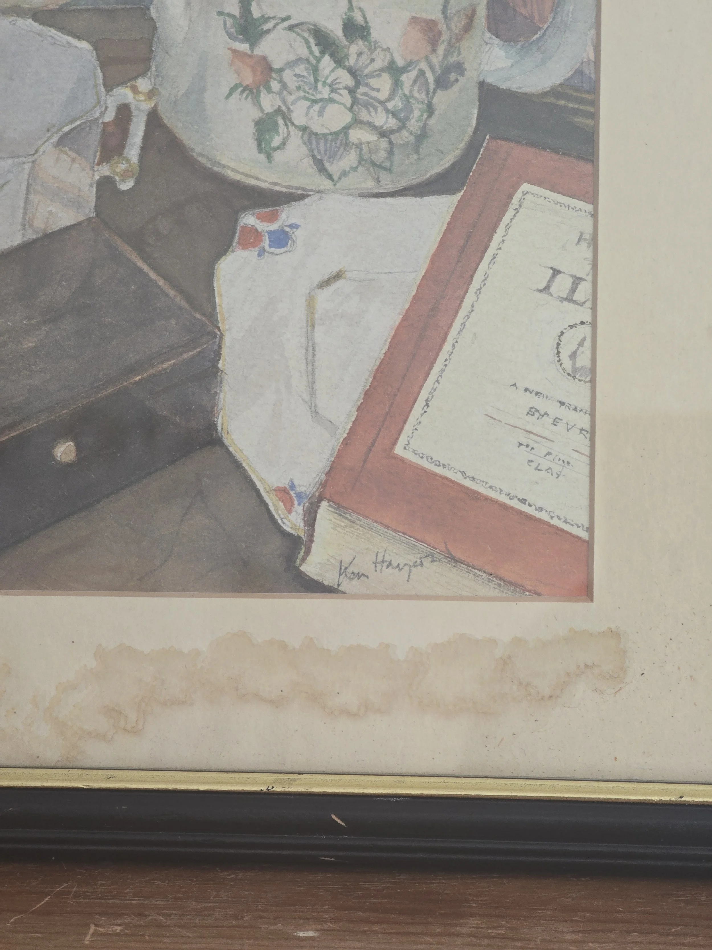 Signed original still life watercolour depicting a floral jug, folded textile and book in soft muted colours, presented in a vintage frame with aged mount.