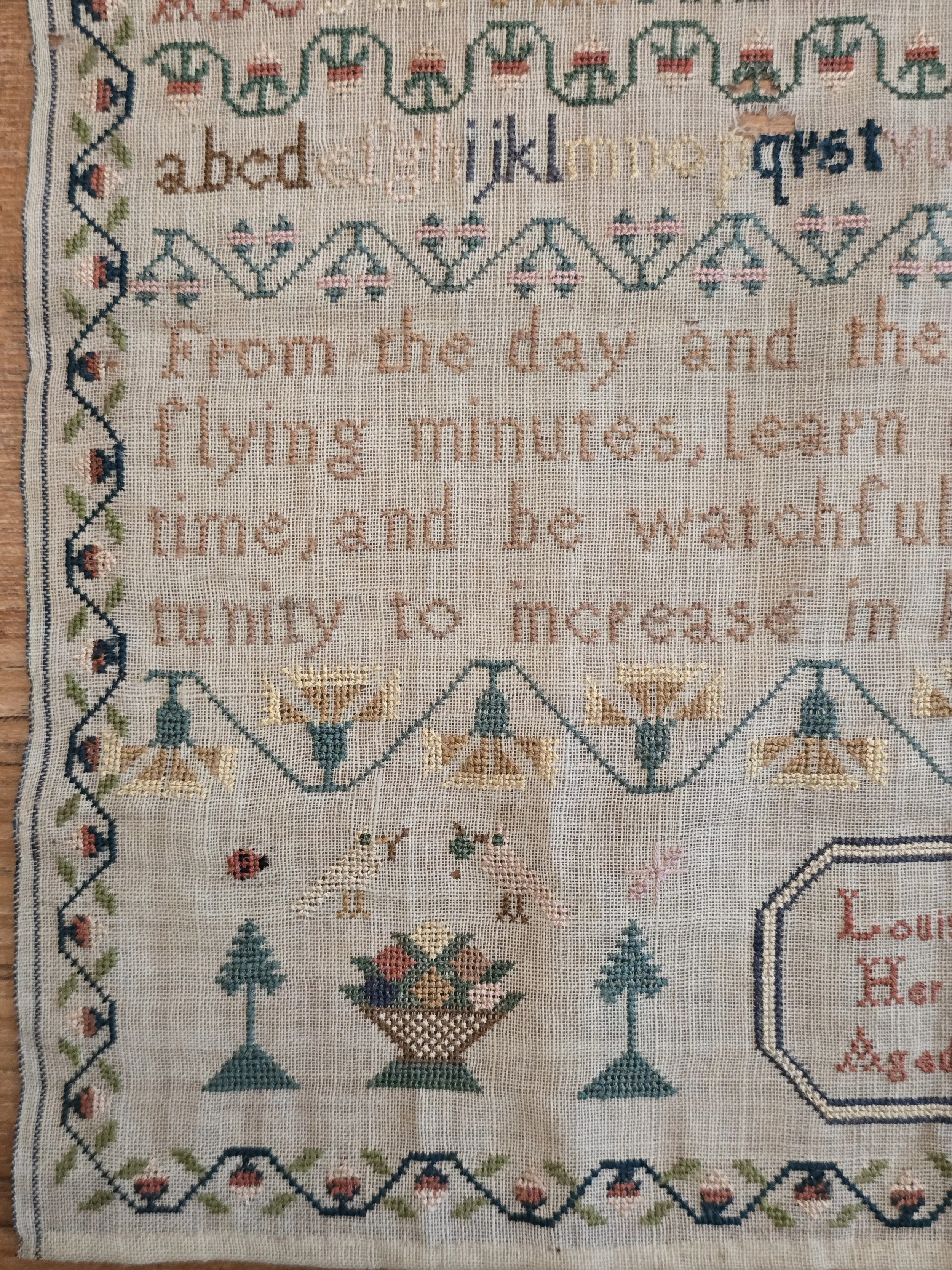 Antique schoolgirl sampler stitched by Louisa Boone aged 9 years with decorative borders, alphabets and floral motifs.