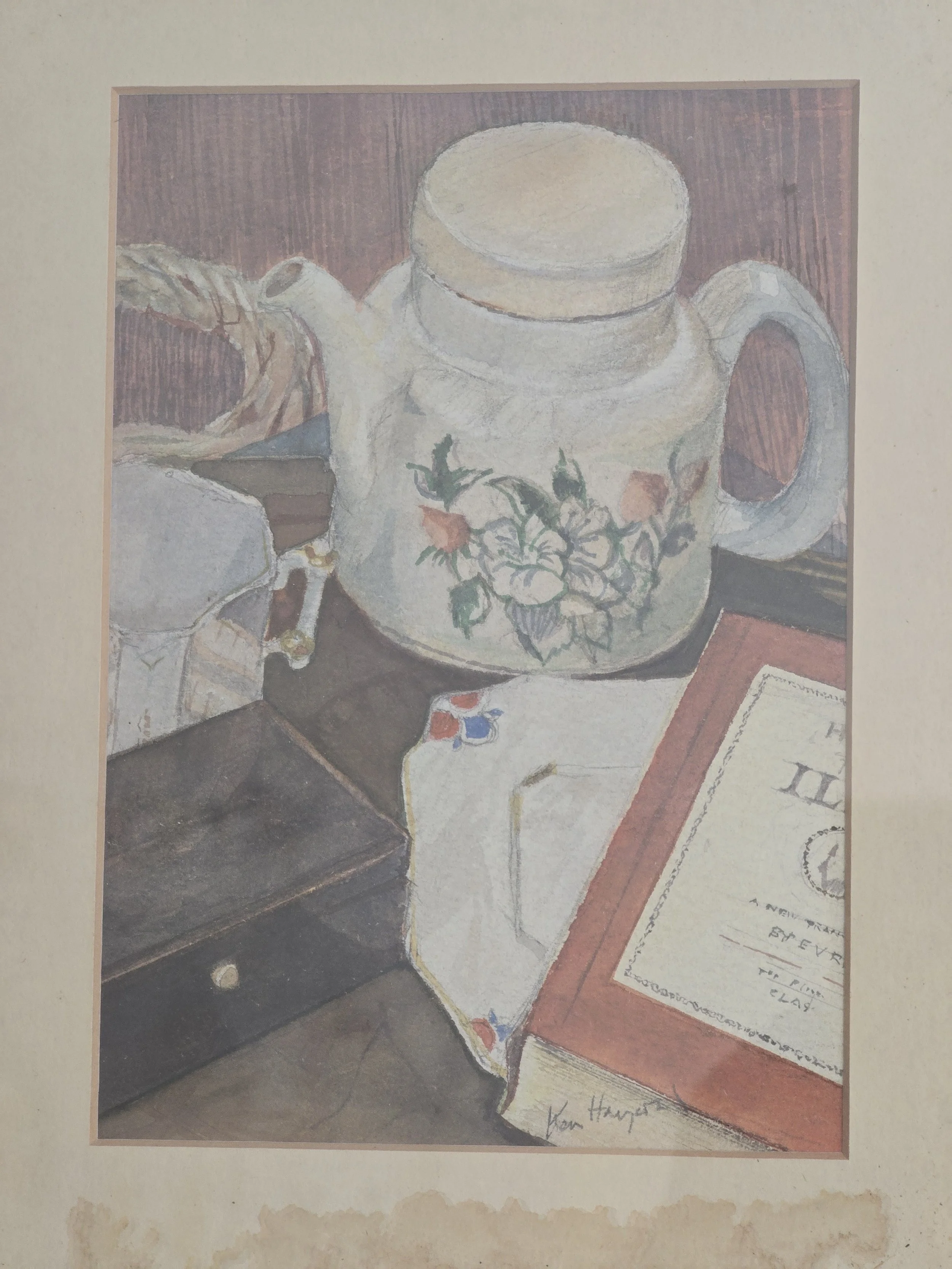 Signed original still life watercolour depicting a floral jug, folded textile and book in soft muted colours, presented in a vintage frame with aged mount.