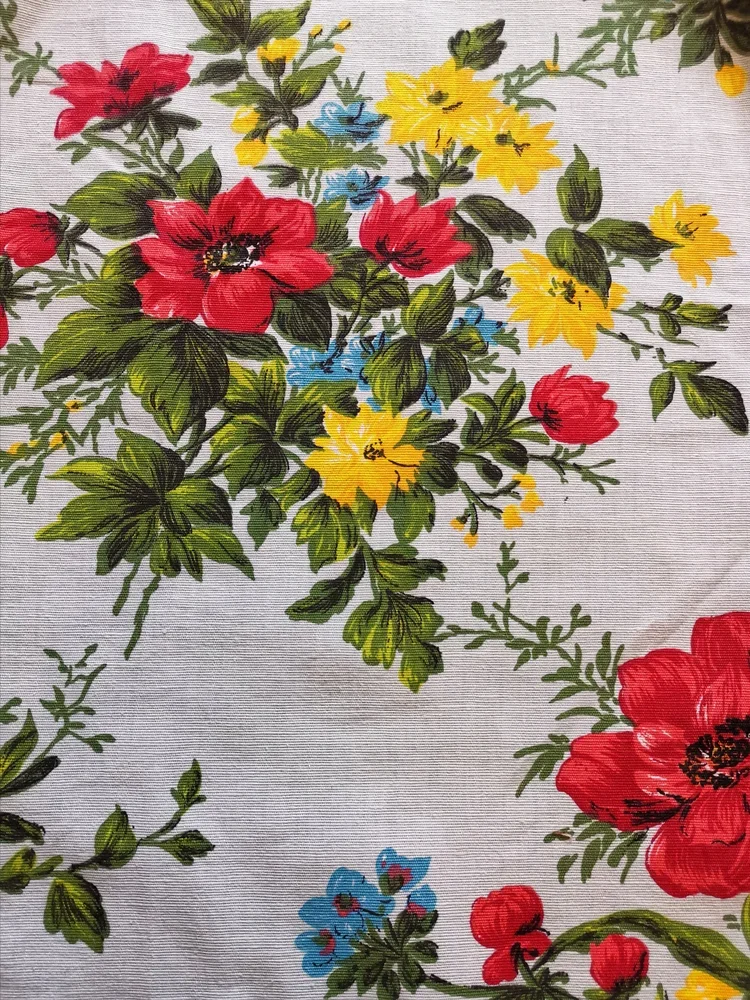 Red poppy and yellow flowers with green leaves on textured vintage floral cotton fabric.