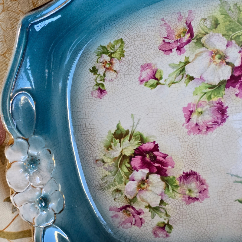Vintage floral ceramic tray with petrol blue glaze, pink flowers and raised white floral details with aged crazing.