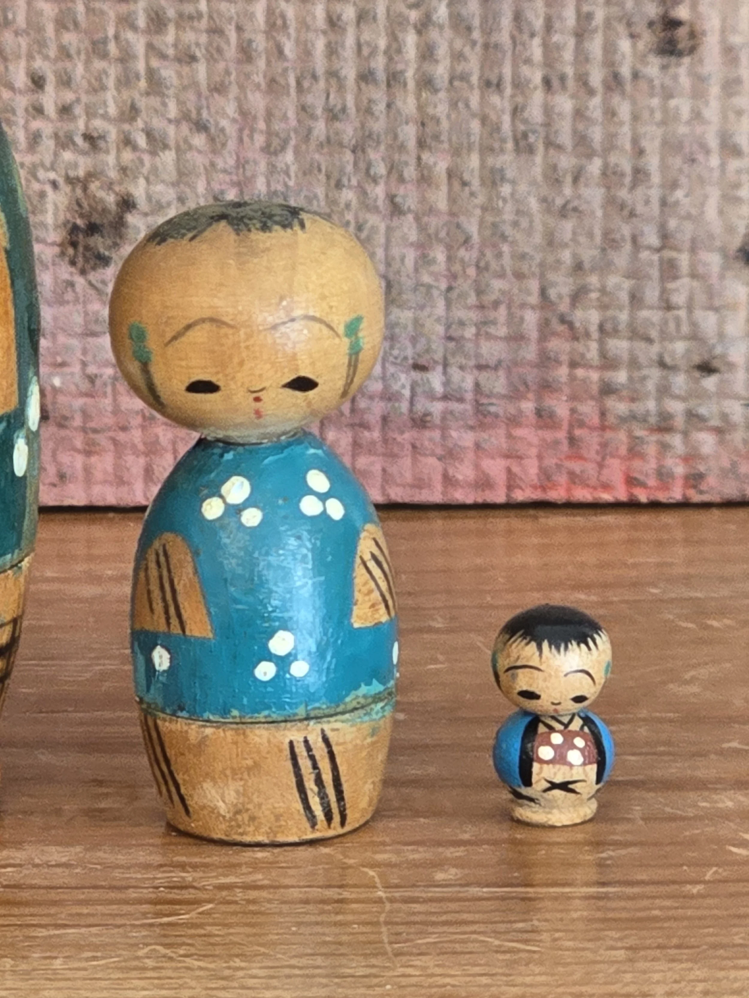 Medium and miniature Japanese kokeshi dolls revealed from inside the nesting set.