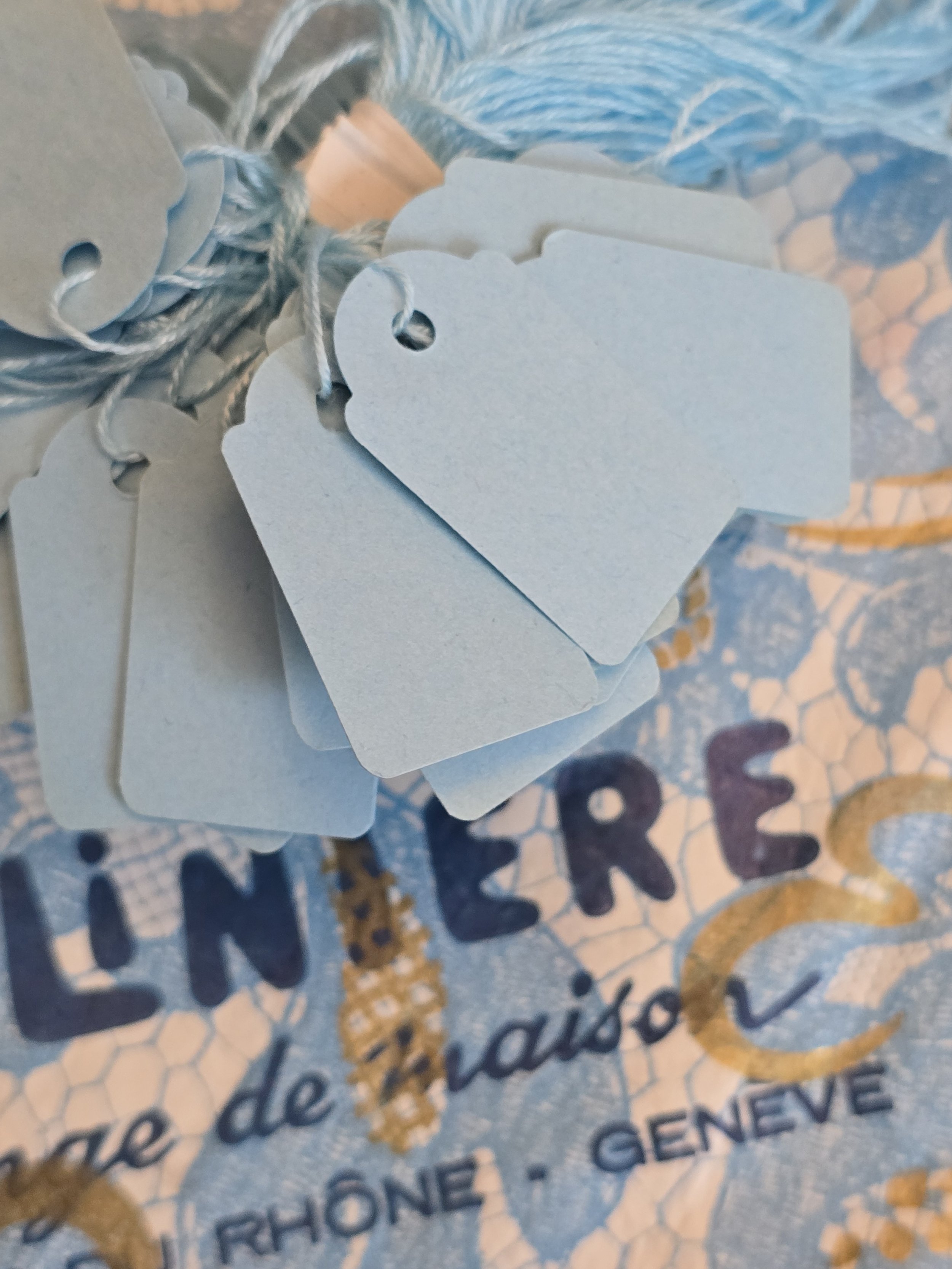 Close-up of unused vintage French powder blue shop price tags showing their shaped edges and original string ties.