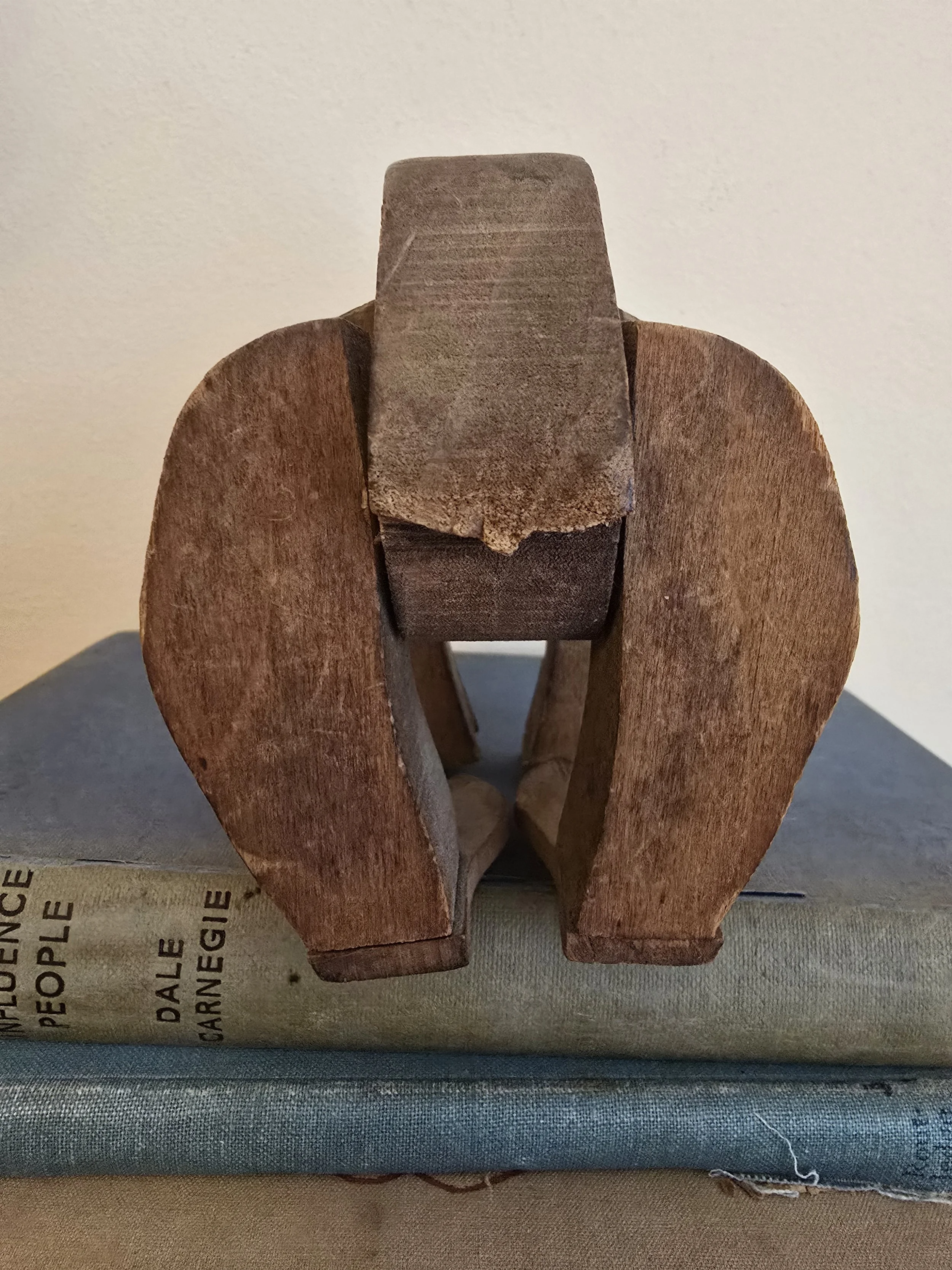 Rear close-up of the antique articulated wooden bear showing curved back and simple tail shape carved into the wood