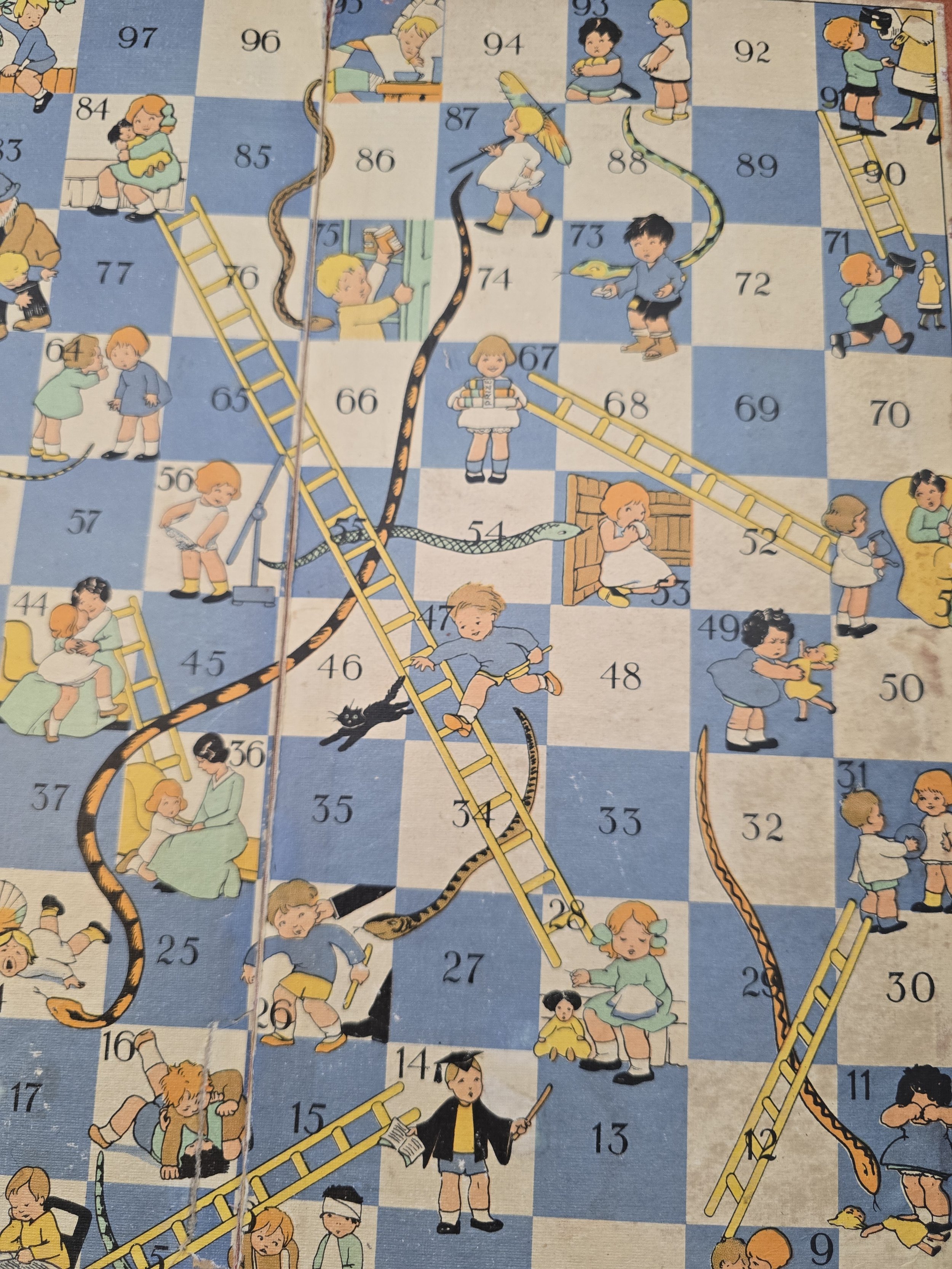 Detail of vintage Snakes and Ladders board with large painted snakes and yellow ladders