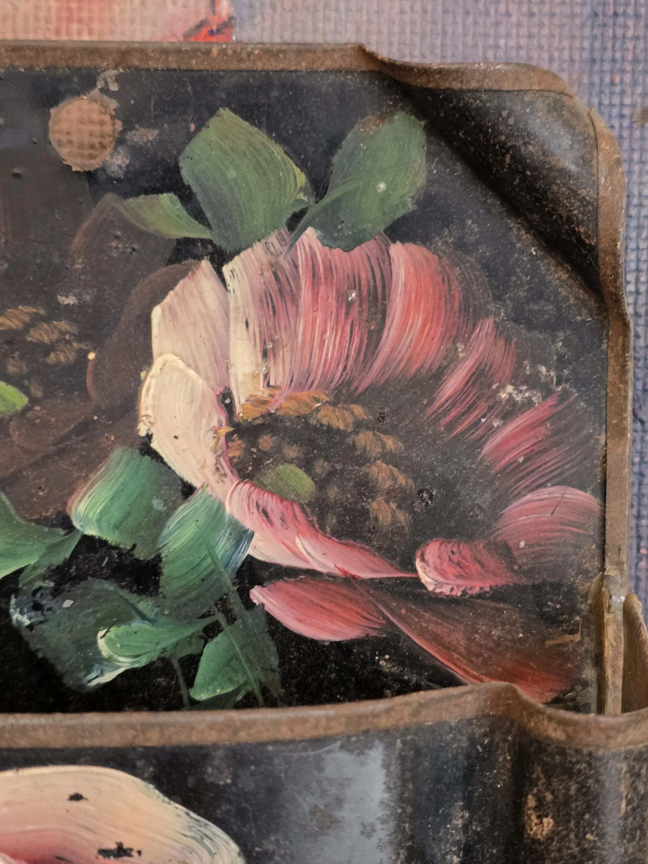 Decorative black metal wall pocket with pink floral folk art painting and rustic wear.