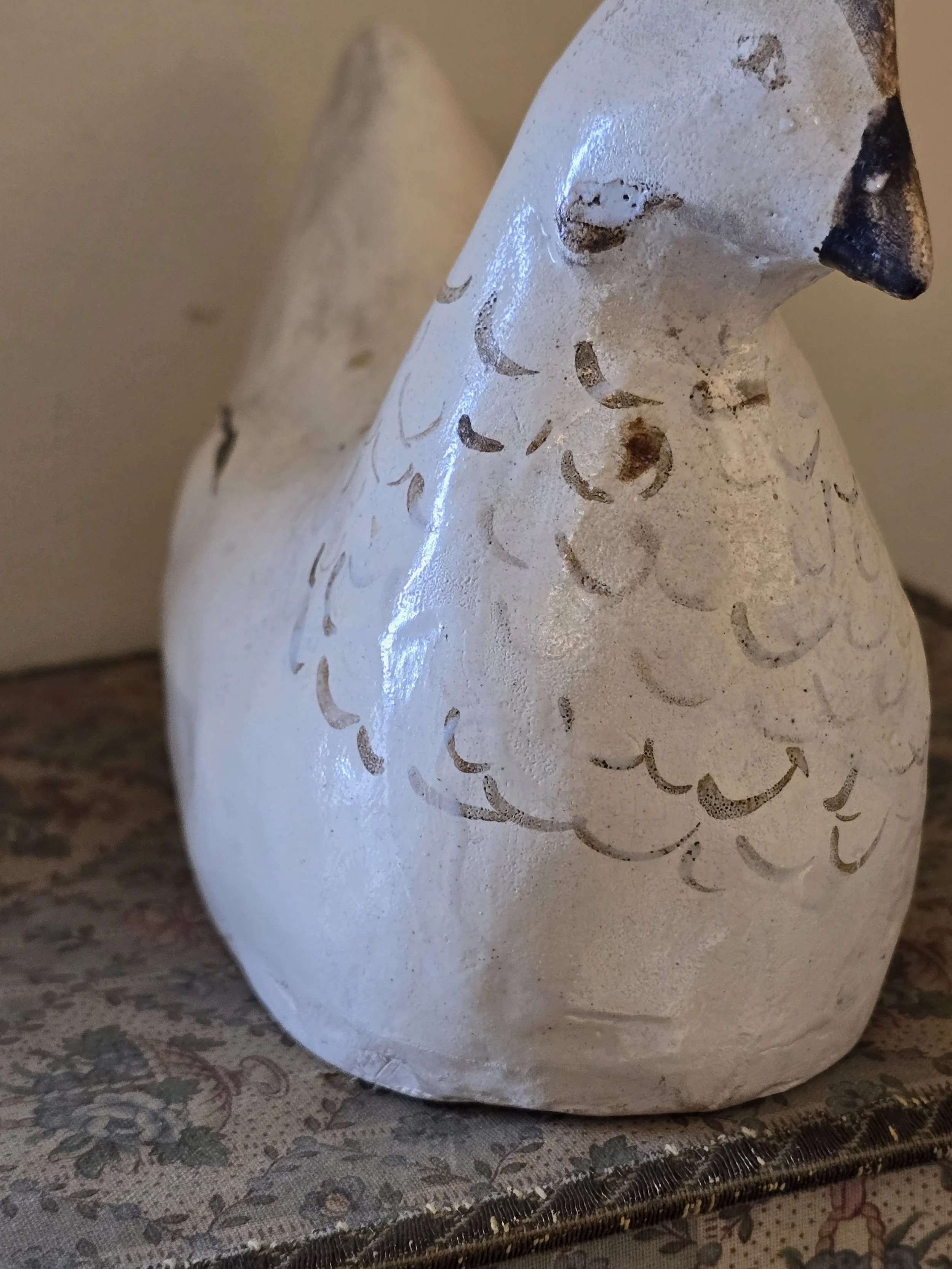 Front view of old painted hen showing rounded body and faded feather decoration across the breast.