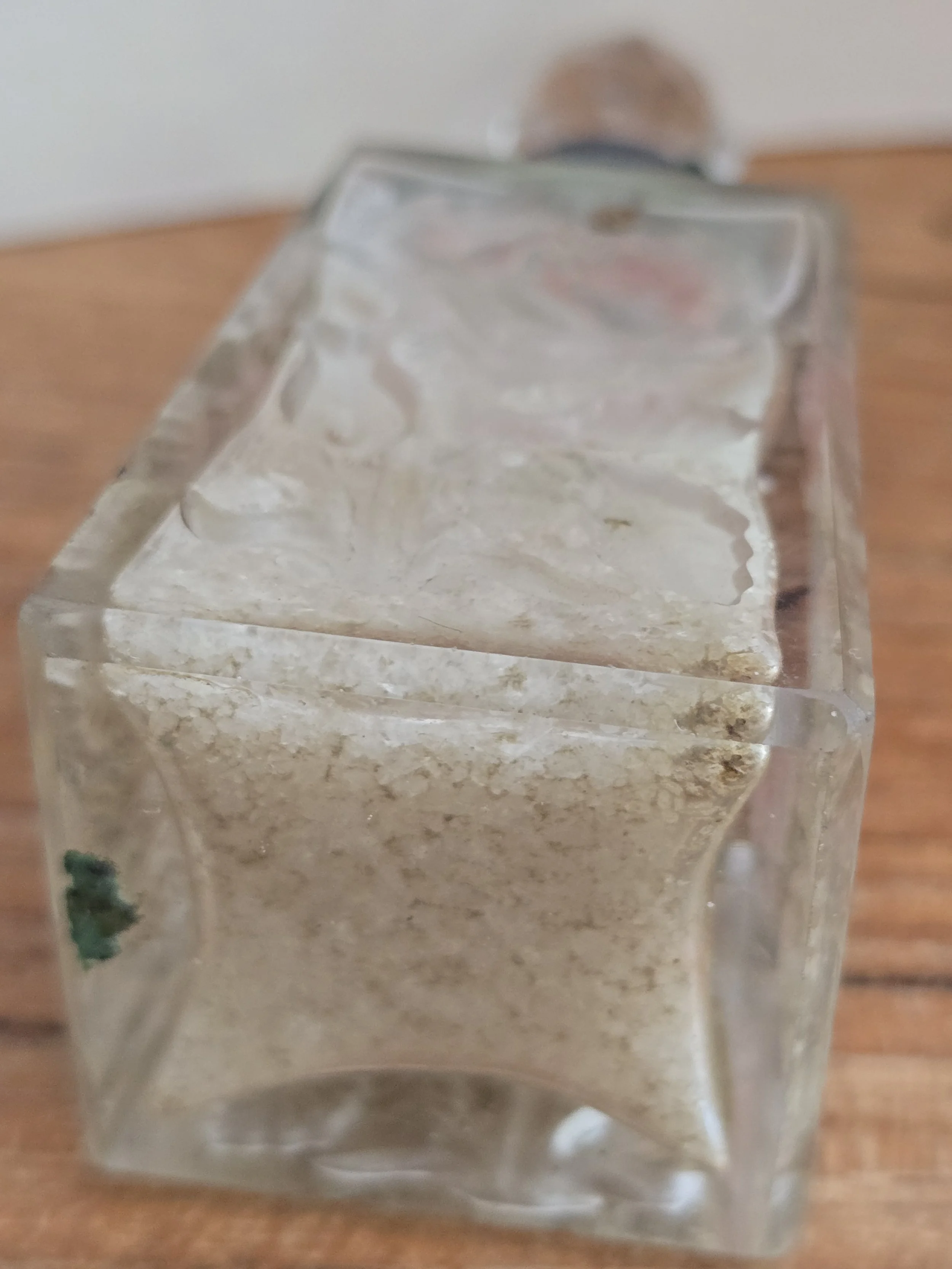 Base of the antique glass perfume bottle showing thick moulded glass and original perfume residue.