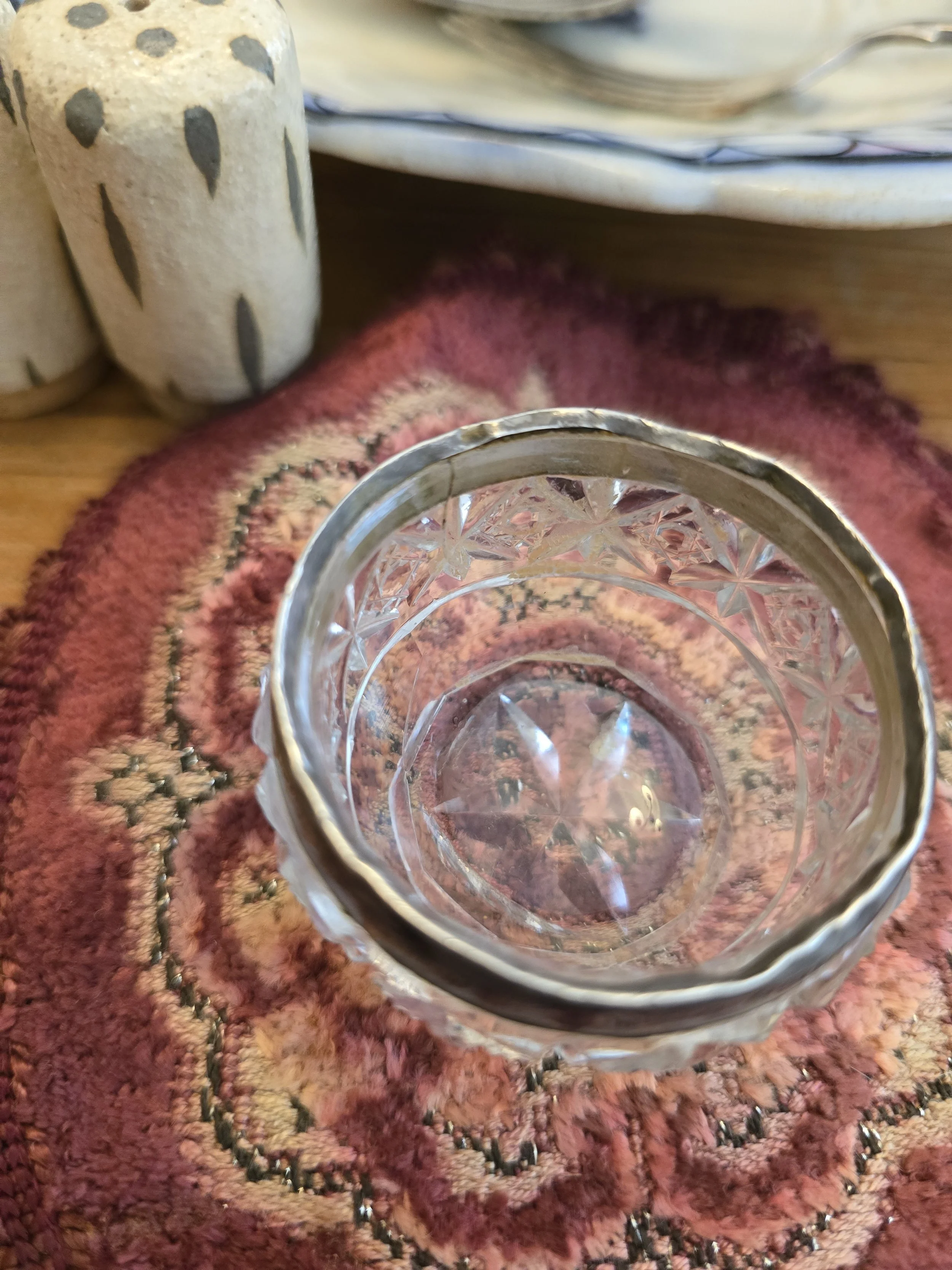 Top view of antique cut glass salt cellar showing star-cut decoration and silver collar.