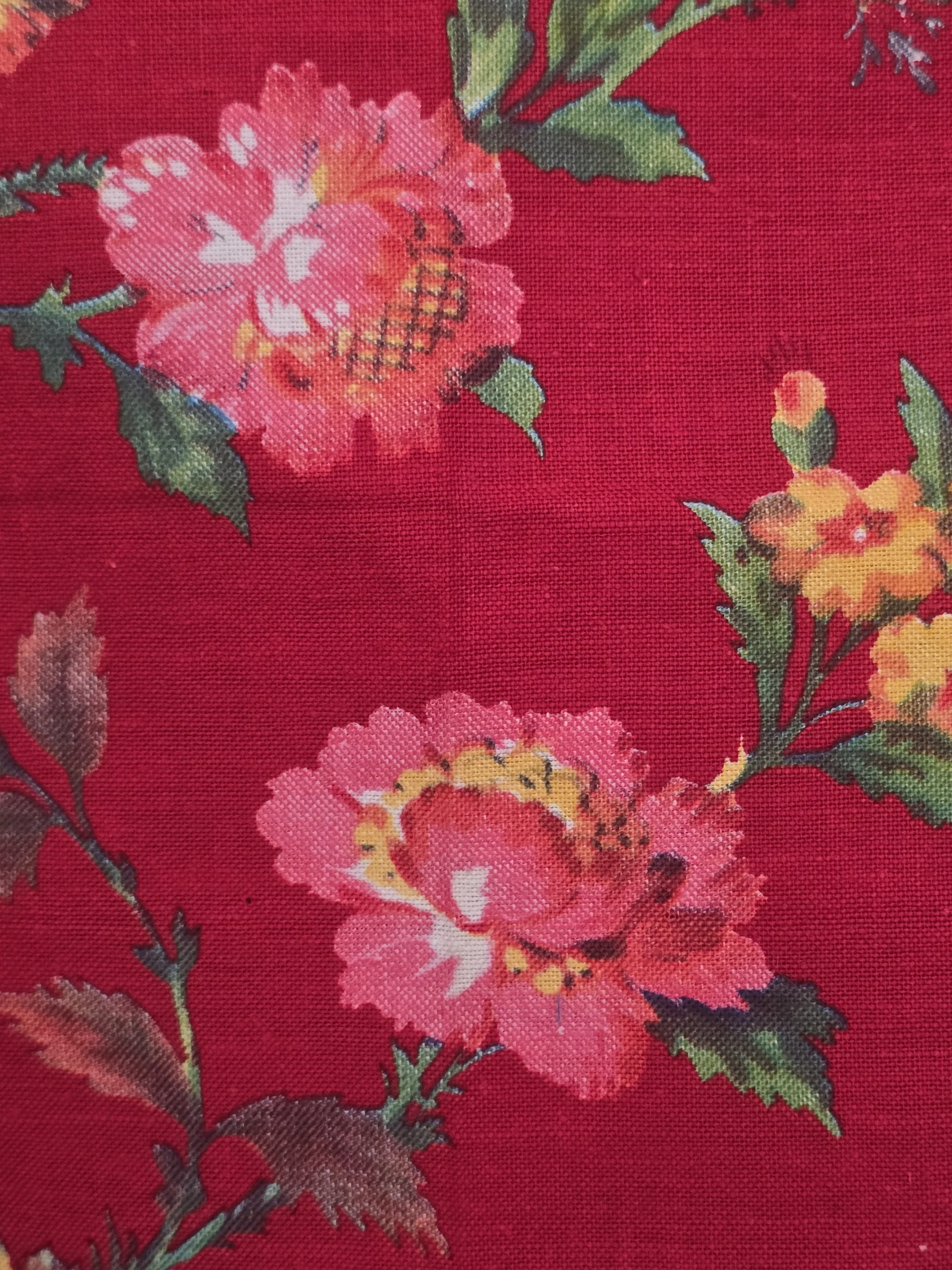 Detail of large pink flowers and yellow blossoms printed on rich red vintage fabric.