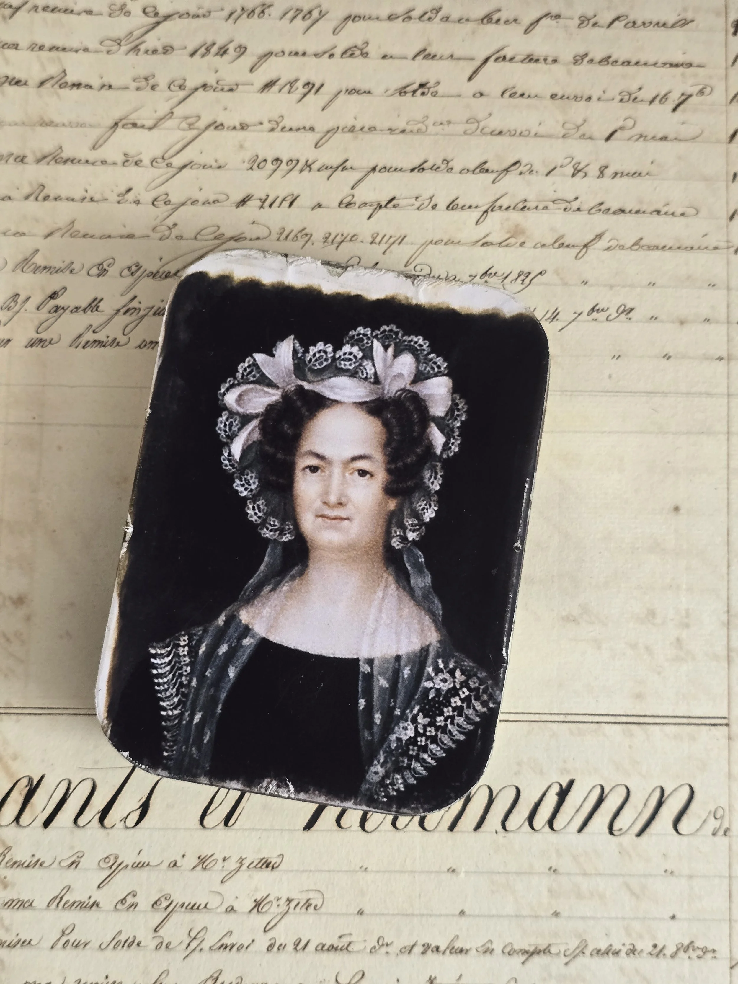 Vintage metal tin reworked with a historic portrait of a woman wearing an elaborate lace and ribbon headdress.