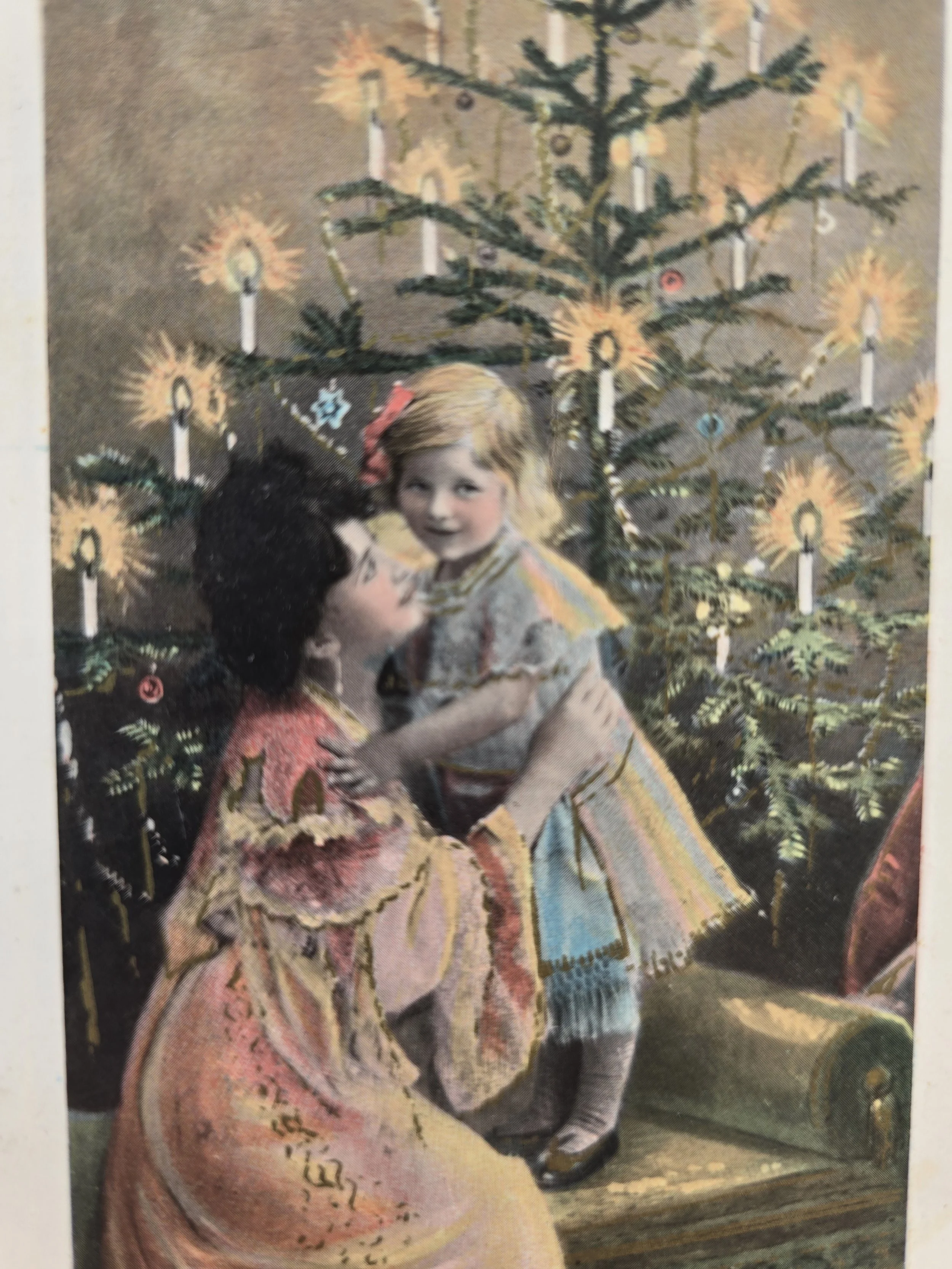 Early 1900s Christmas postcard with little girl and mother beneath decorated tree
