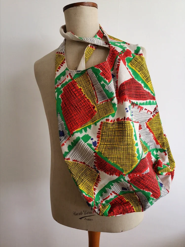 Detail of the mid-century abstract print fabric with red, yellow, green and black shapes.