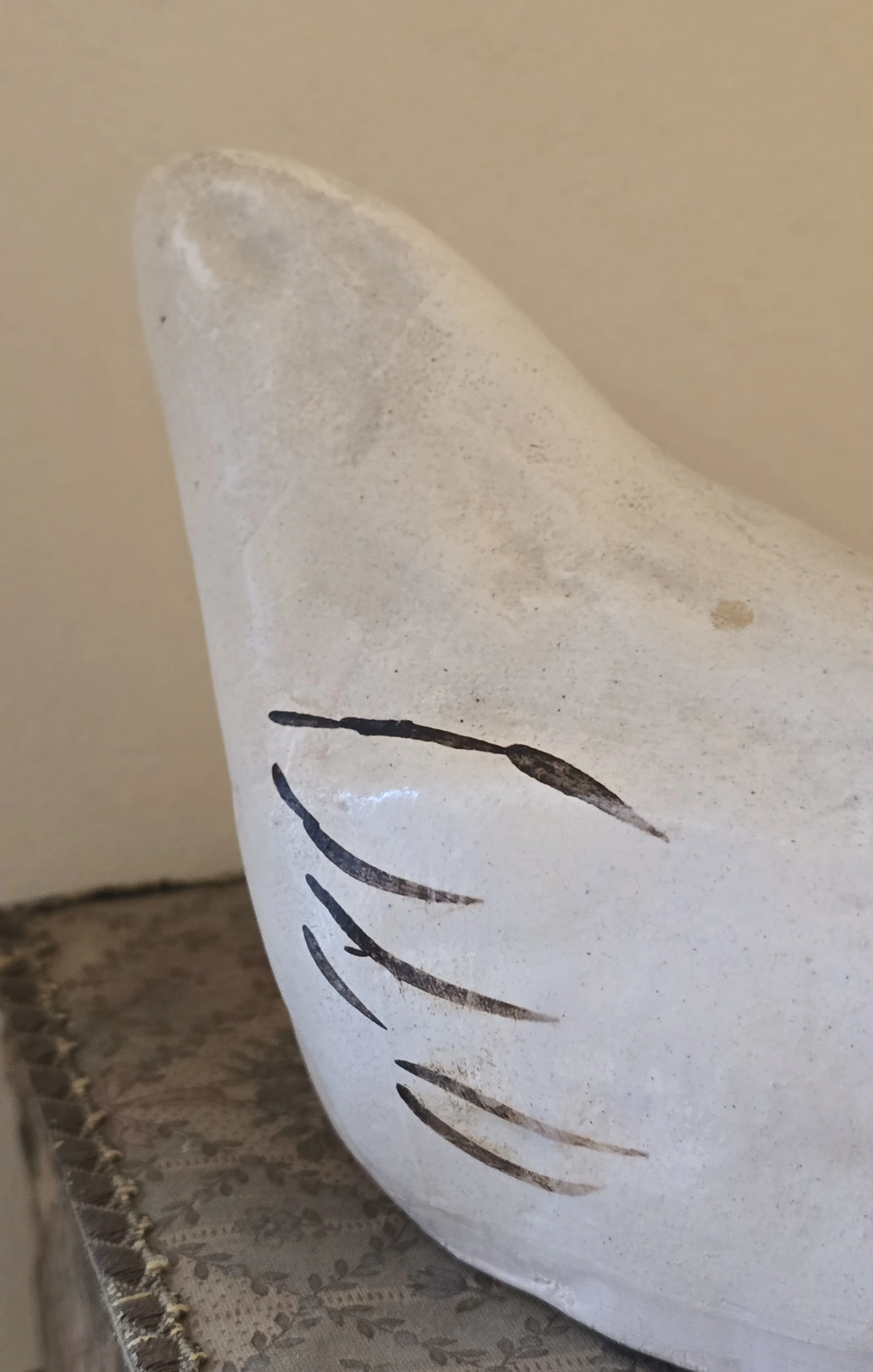 Close-up of the worn white painted surface and simple curved feather markings on the hen.