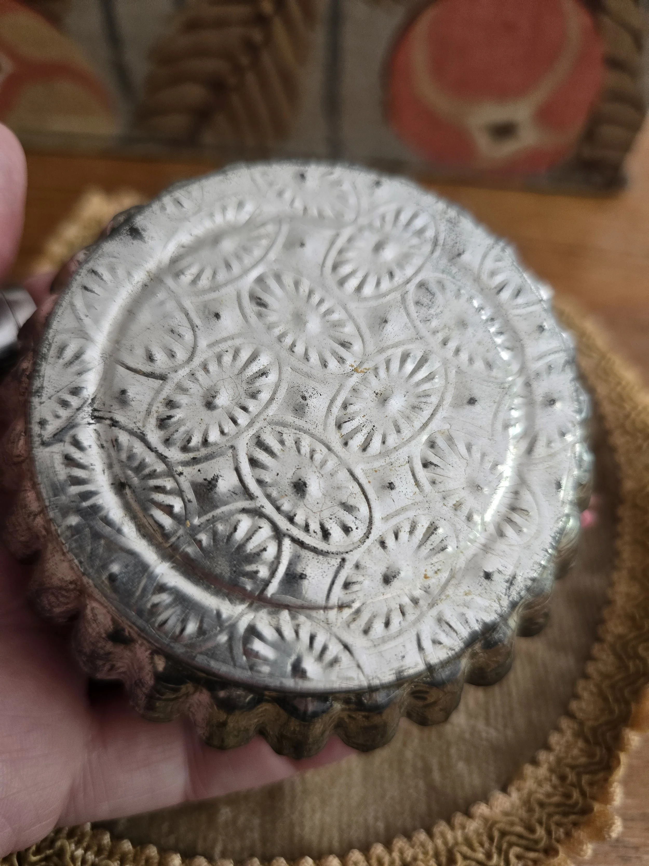 Engraved vintage metal tart mould forming the base of the handmade pincushion.