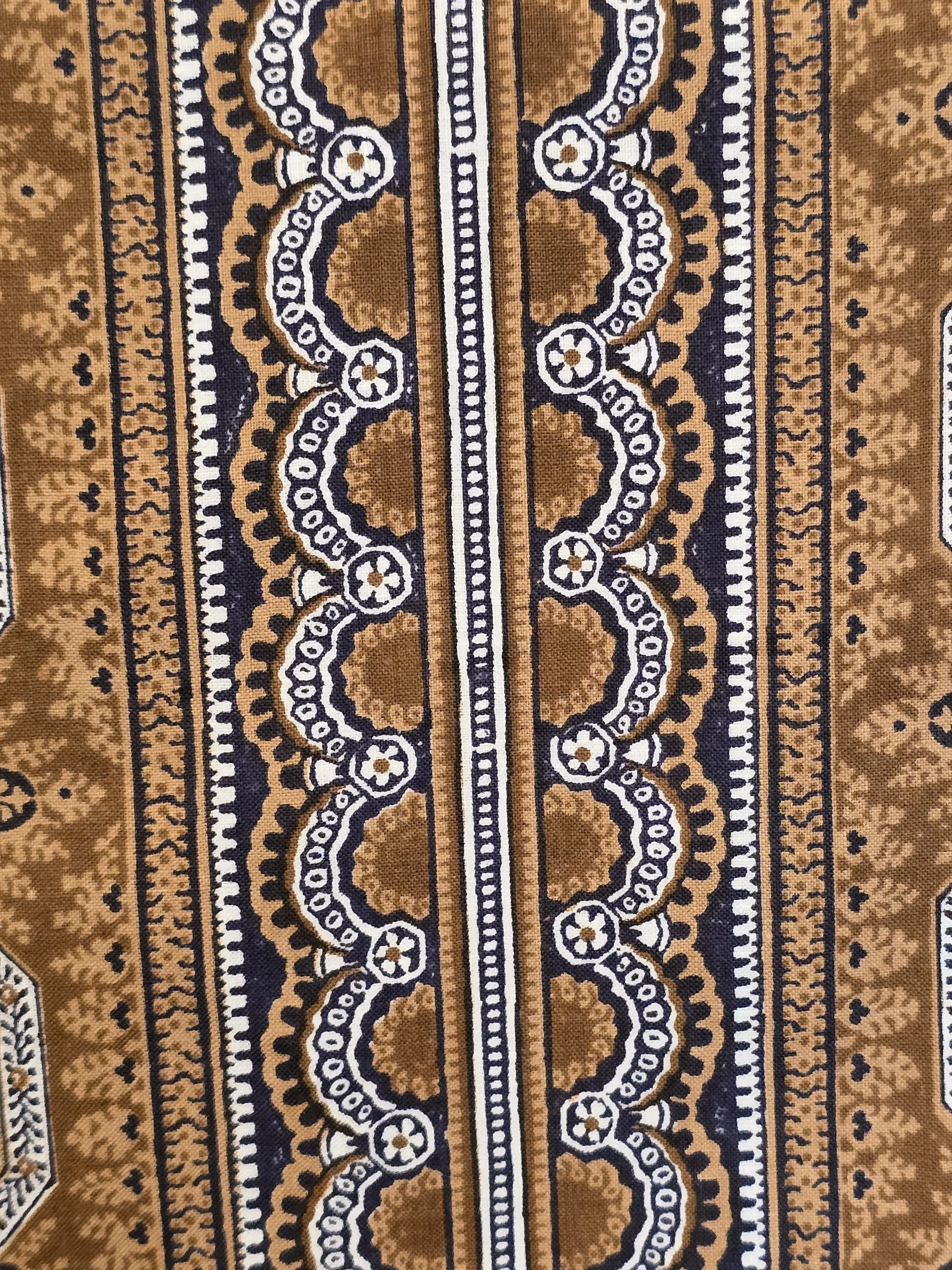Close-up of geometric floral medallions printed in ochre, cream and dark navy.